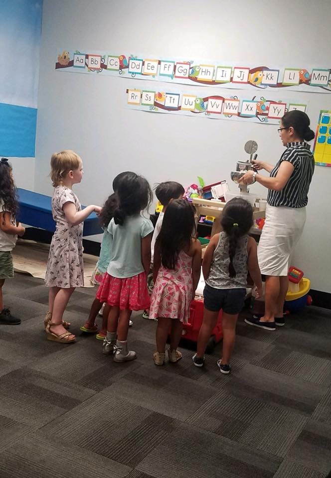 Adult showing children an object in a classroom