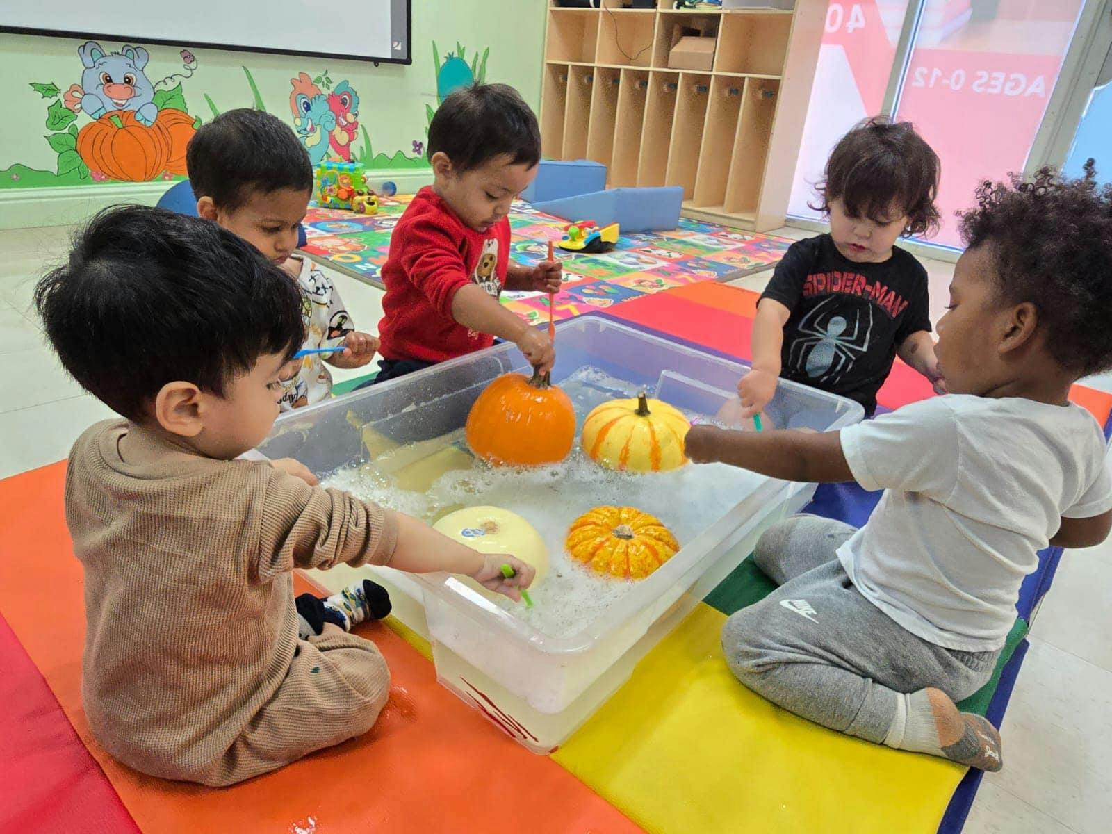 Children playing with pumpkins in a water bin