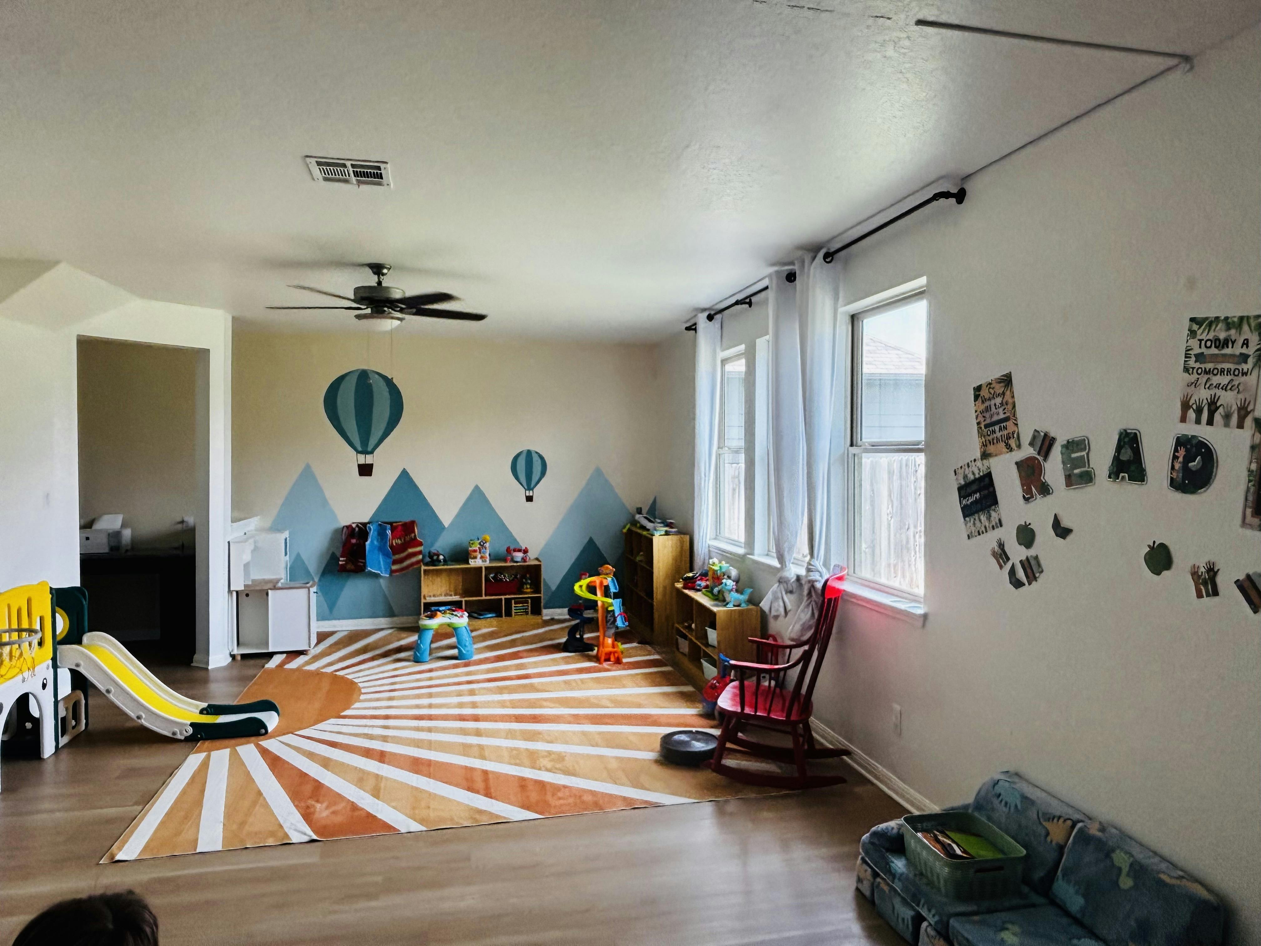 Playroom with toys, a child-sized slide, and wall art