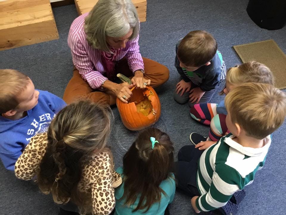 Adult and children gathered around a pumpkin