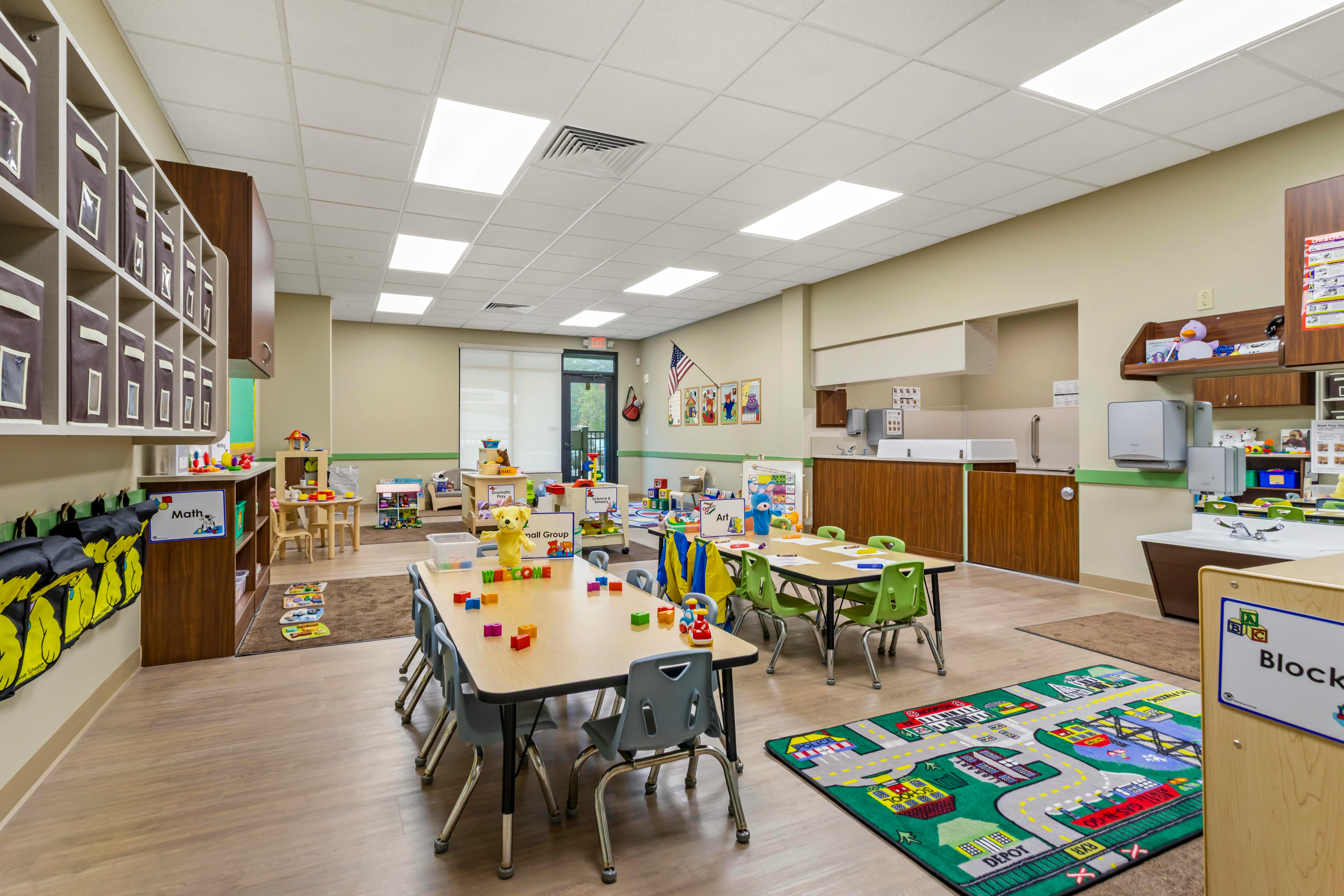 Classroom with child-sized tables and chairs, play areas, and storage cubbies