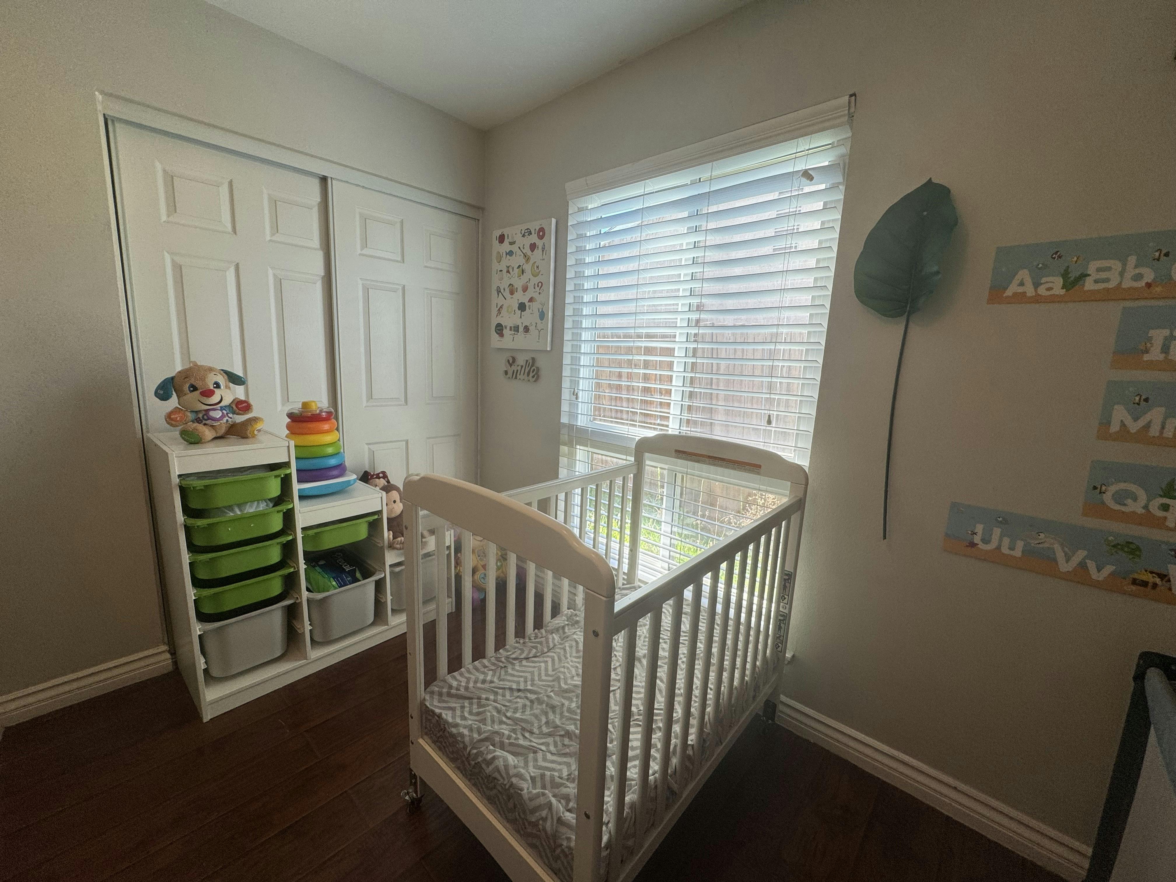 A nursery room with a white crib next to a window with blinds