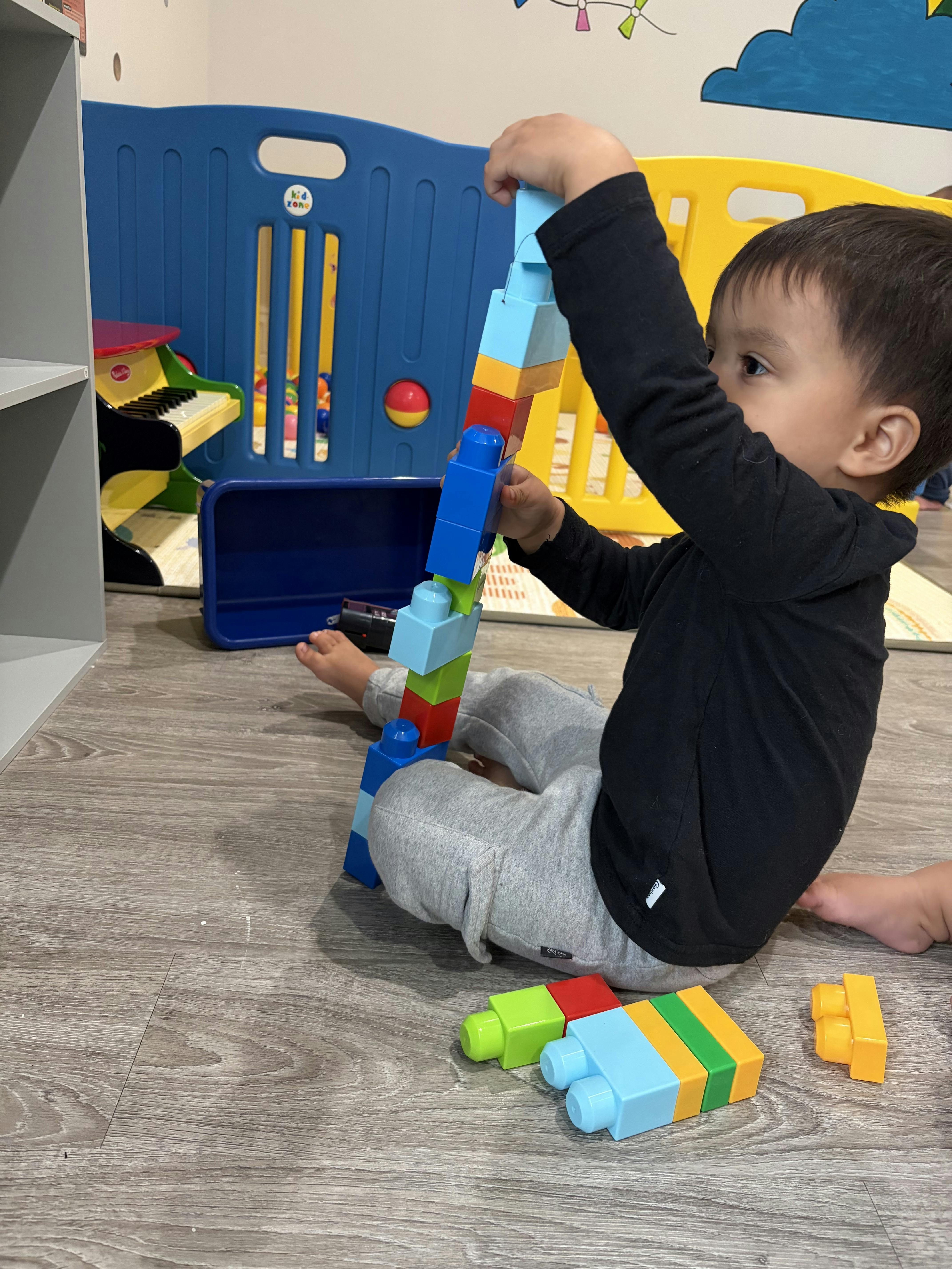 Child building a tall tower with colorful plastic blocks on a play mat
