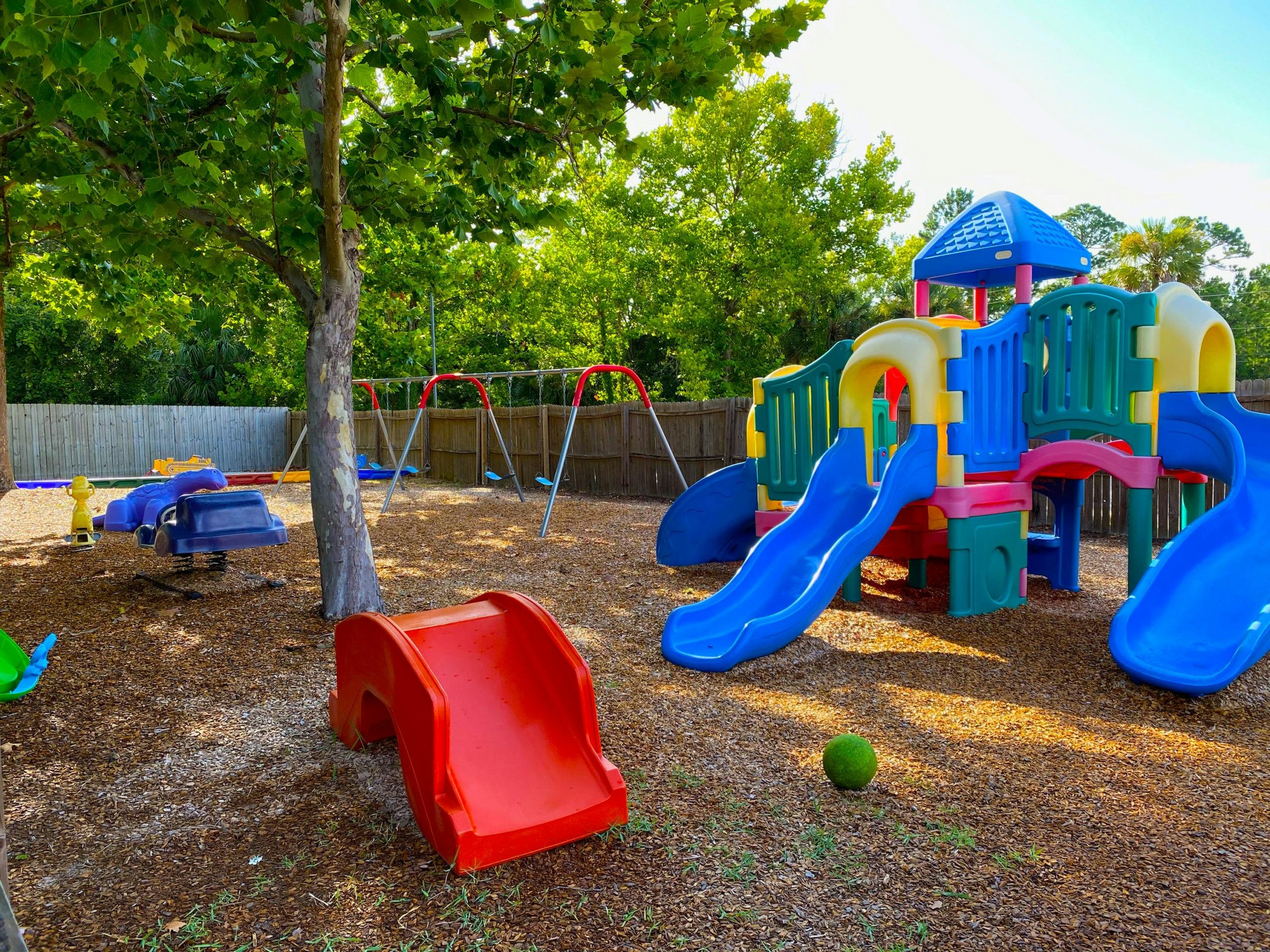 Children's playground with slides, swings, and spring riders on wood chips