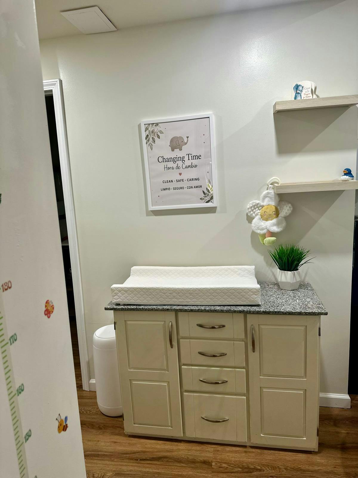 Baby changing station with white pad on dresser, sign above says "Changing Time"