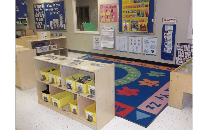An empty classroom with posters on the walls and a colorful rug on the floor