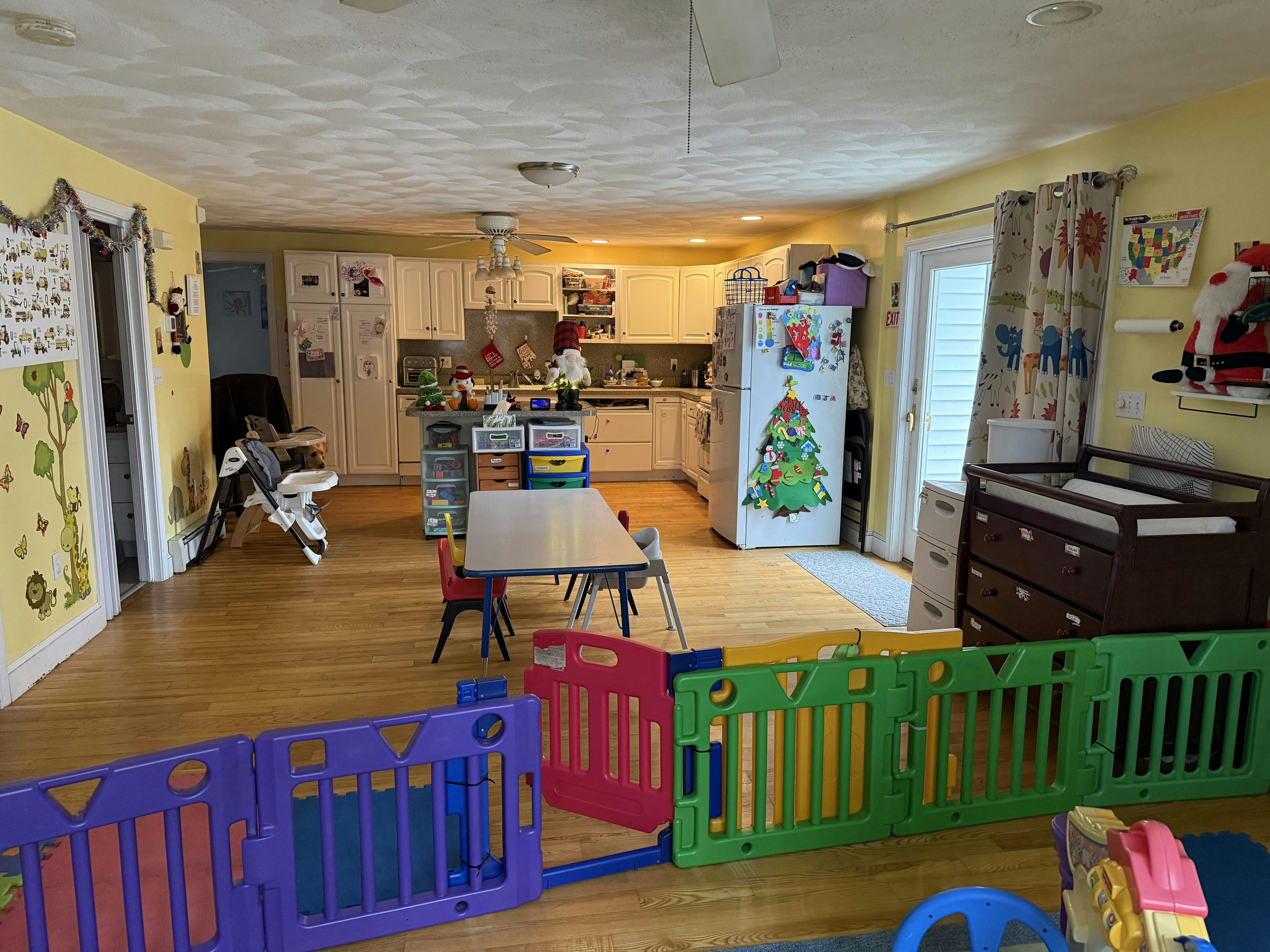 Play area with colorful gates and a table in a room with a kitchen in the background