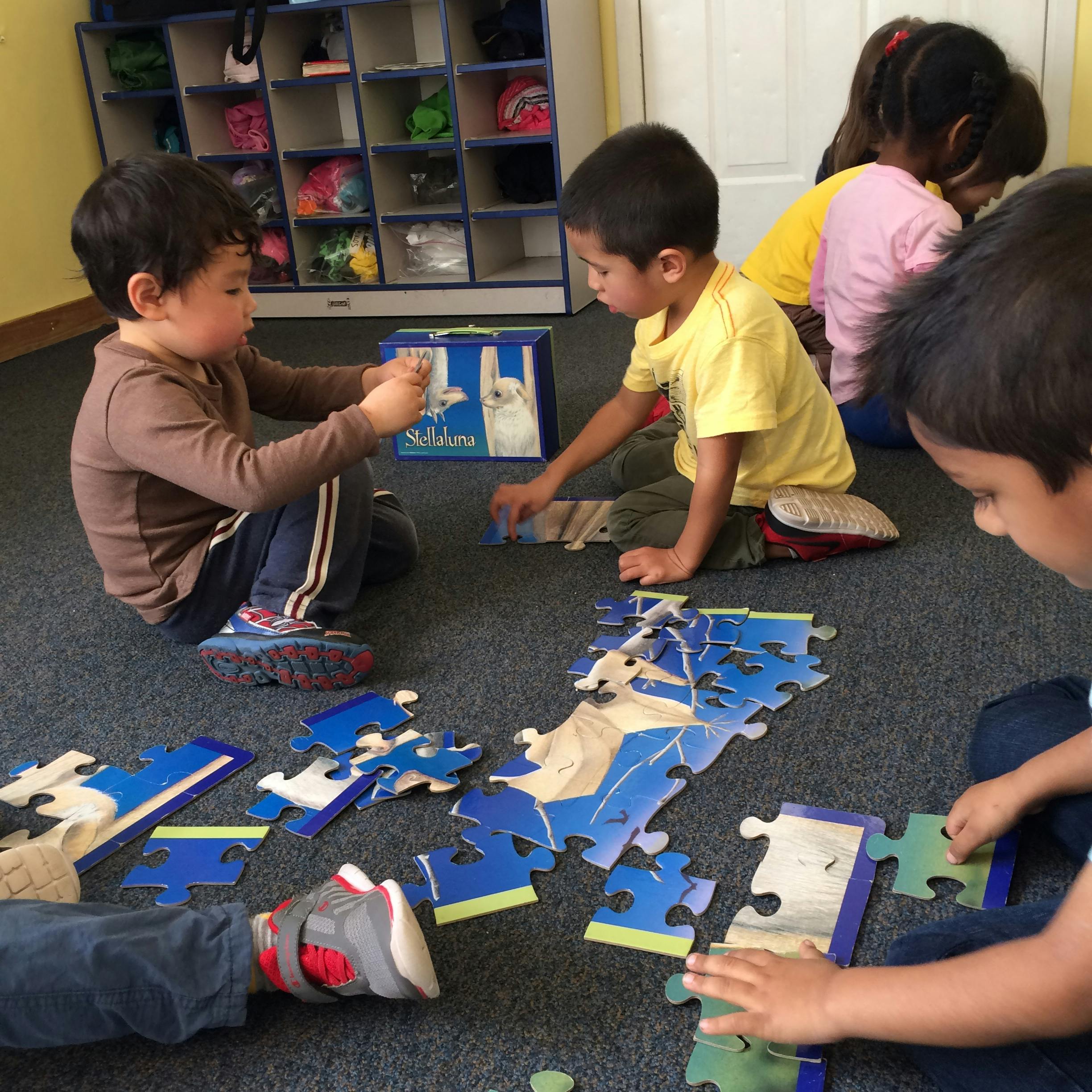 Children on floor assembling a large puzzle