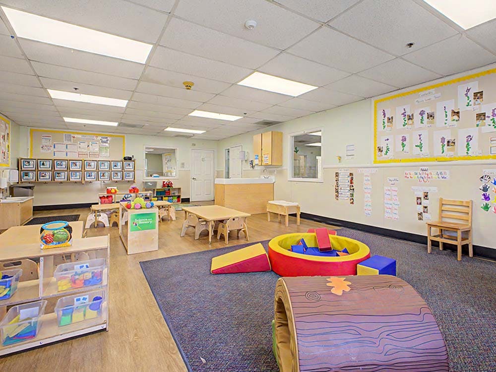 Classroom with small tables, chairs, and soft play equipment