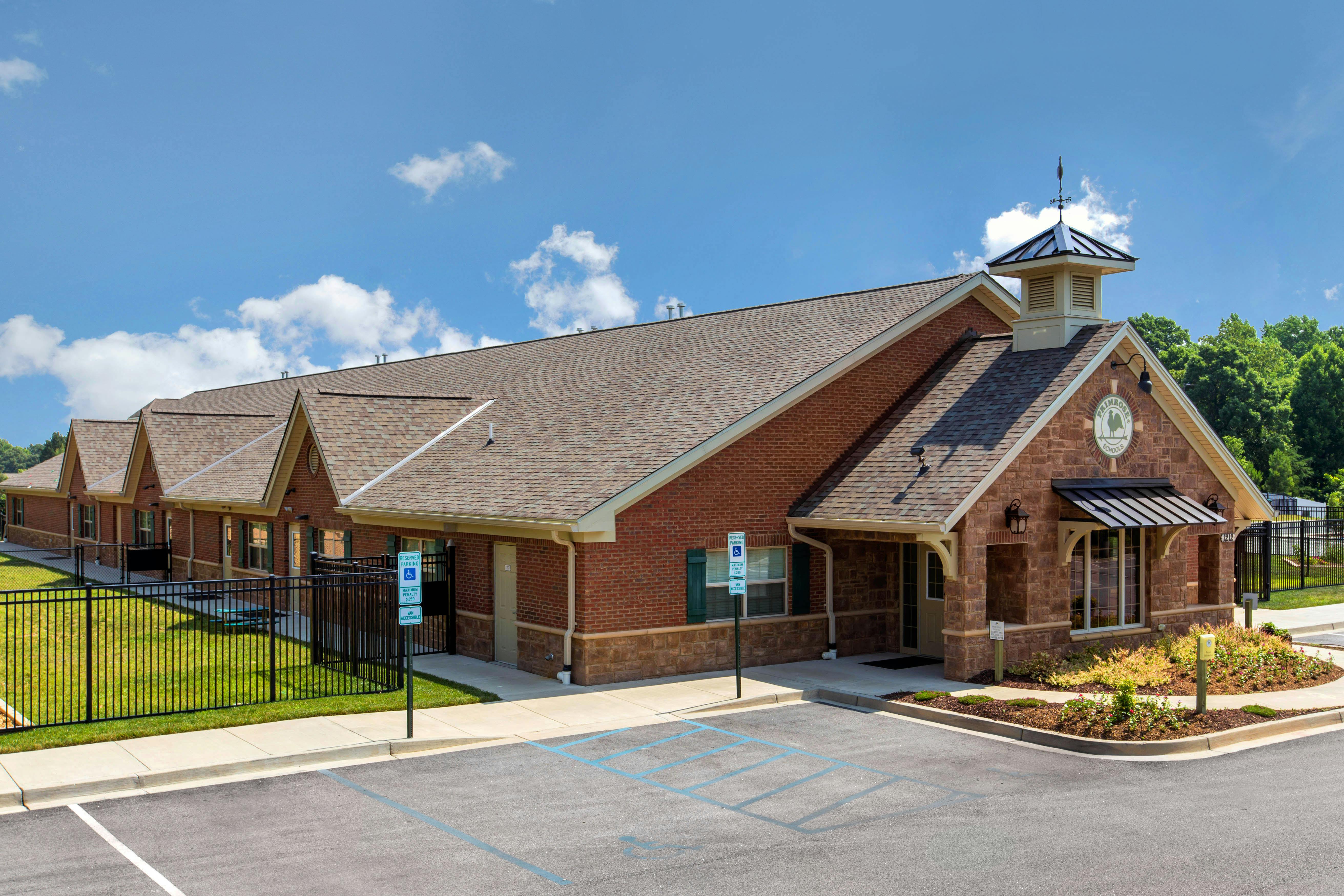 Brick building with a stone facade entrance, cupola, and “Primrose Schools” sign