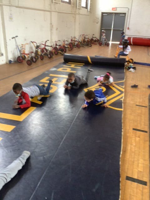 Children crawling on a mat in a gym