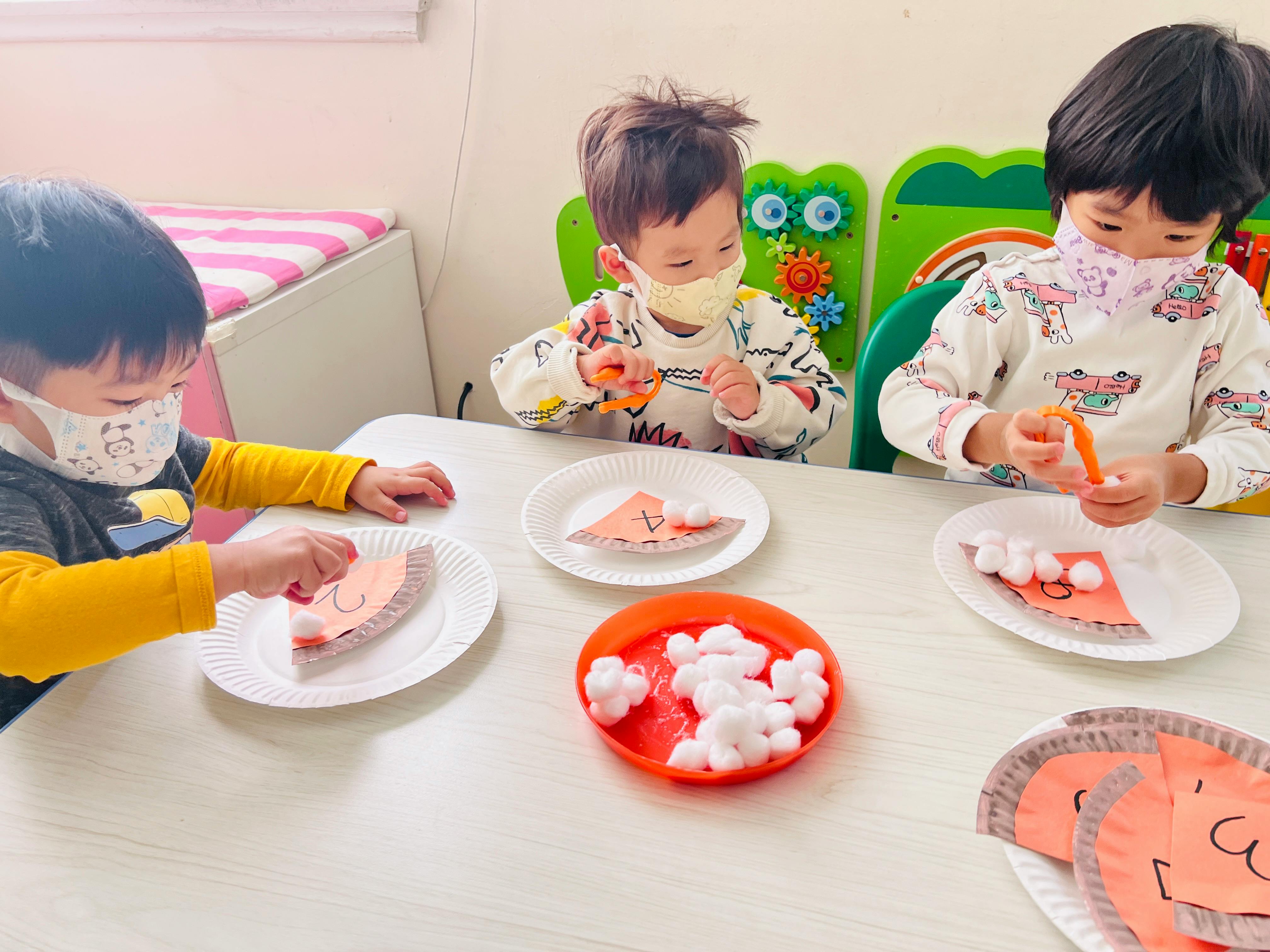 Three children wearing masks doing crafts at a table