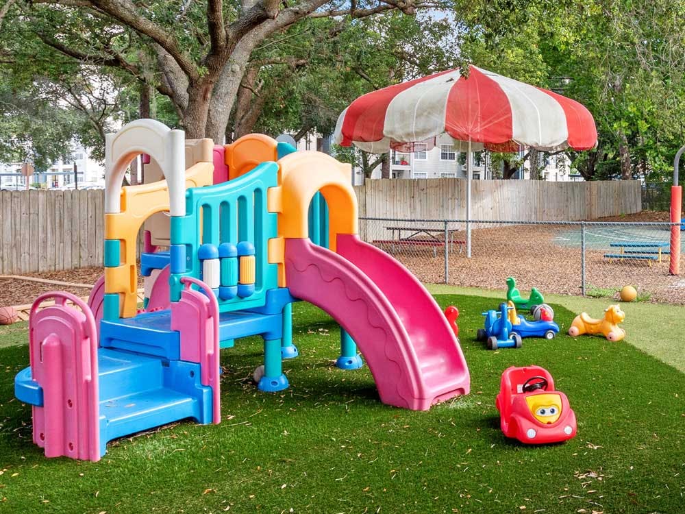 Colorful playground with a slide and ride-on toys on artificial grass