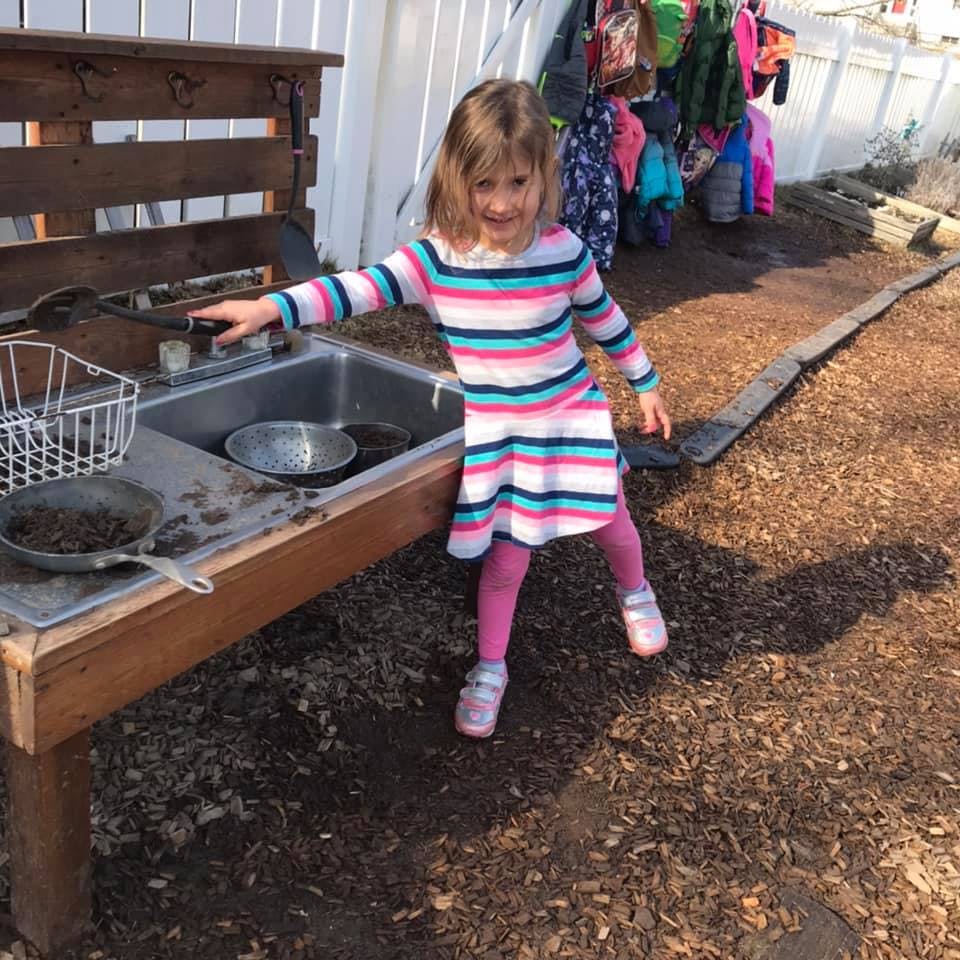 Child playing at an outdoor mud kitchen