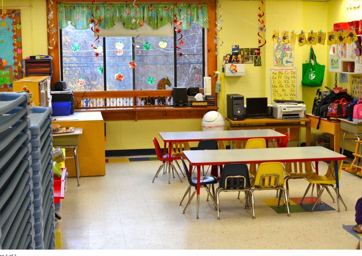 Classroom with small tables and chairs, window with decorations
