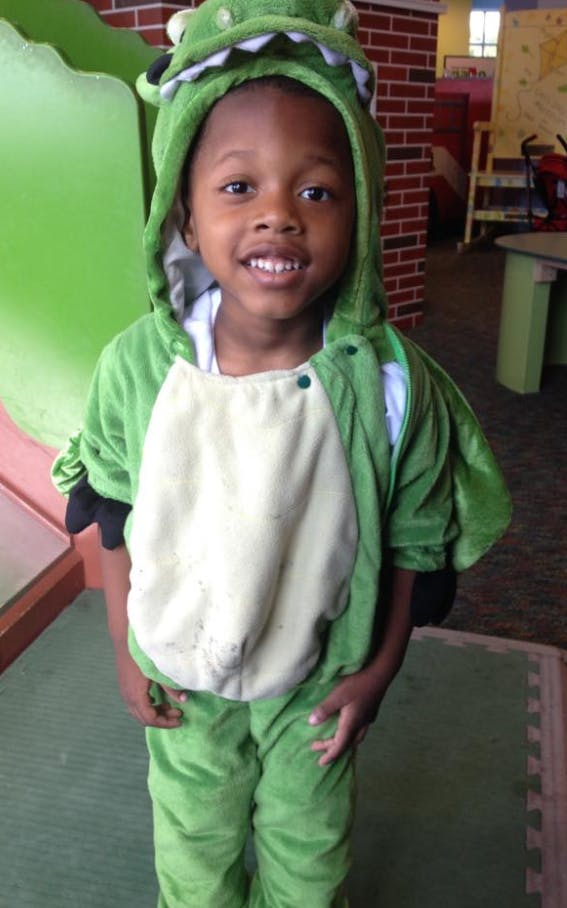 Child in a green dinosaur costume