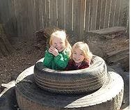 Two children sitting in a stack of tires