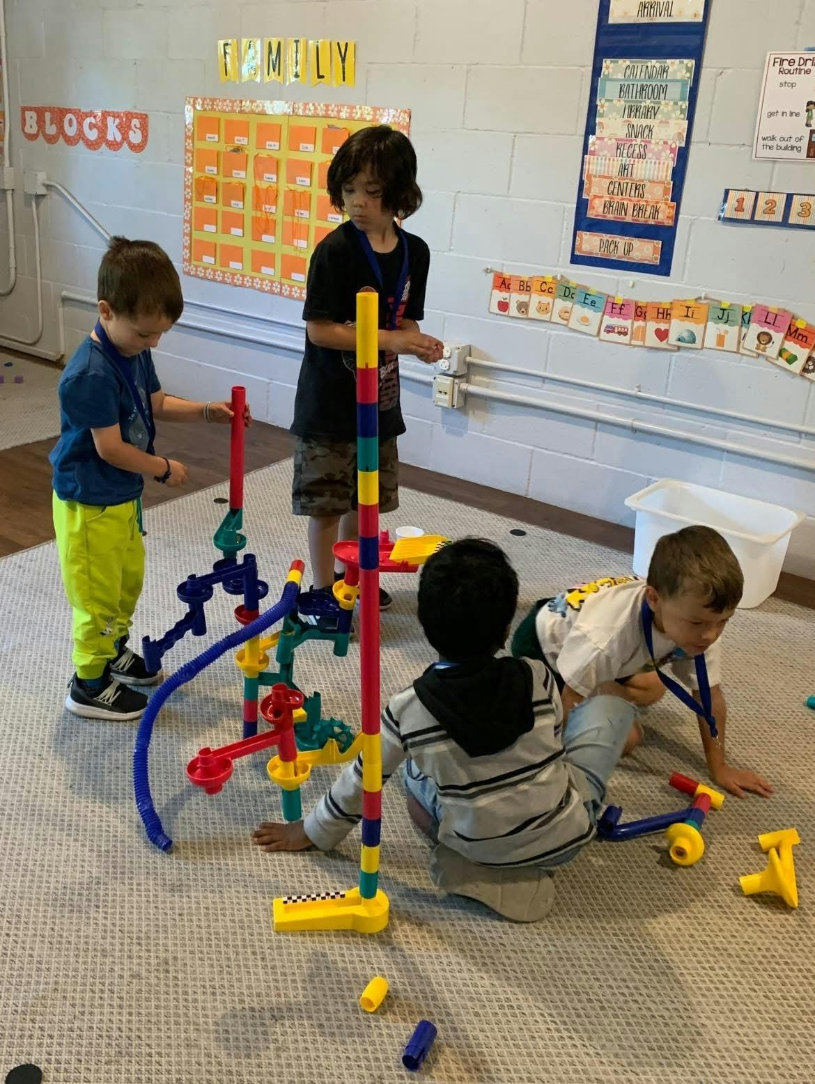 Four children playing with colorful construction toys in a classroom