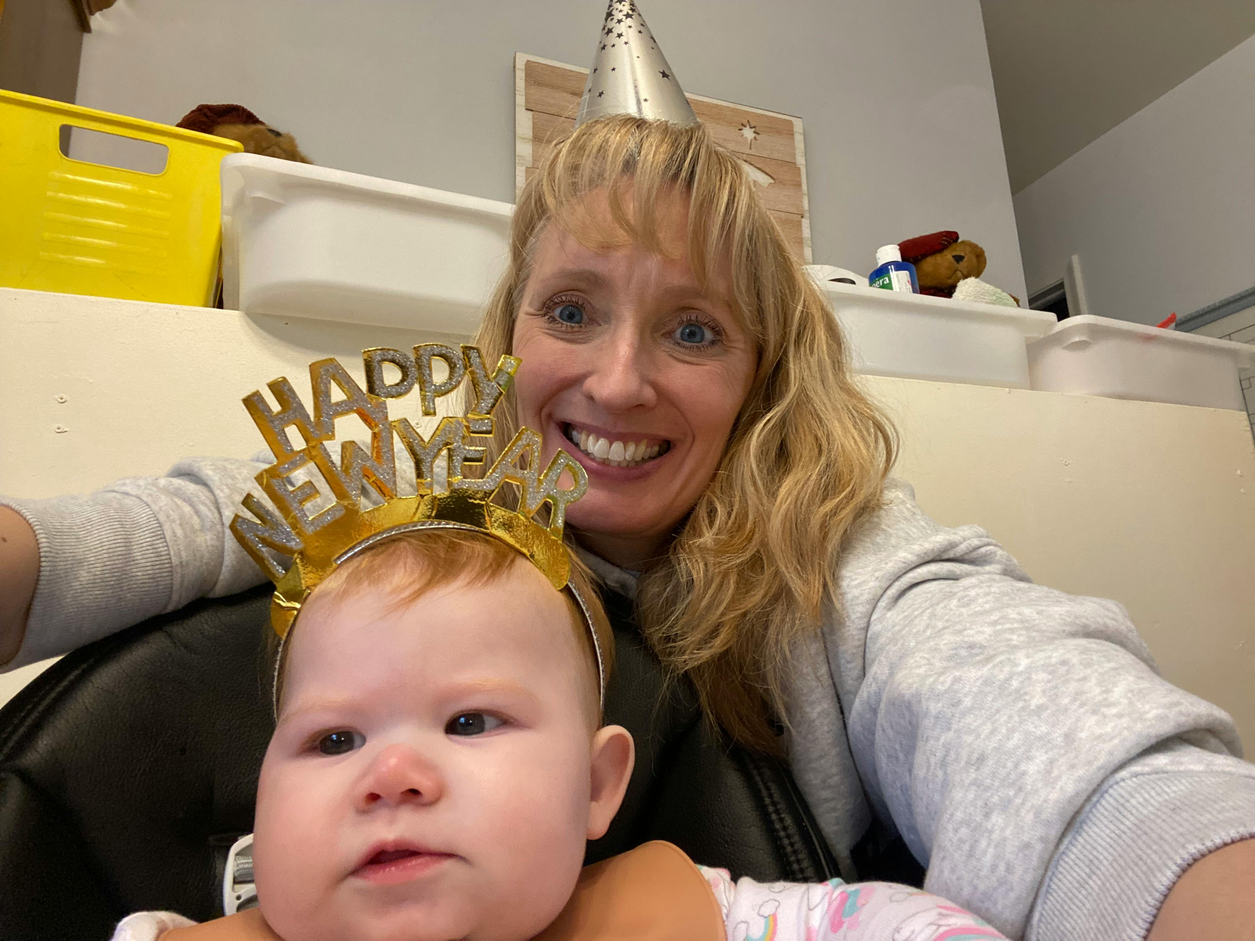 Person and child wearing party hats, child wearing a Happy New Year headband