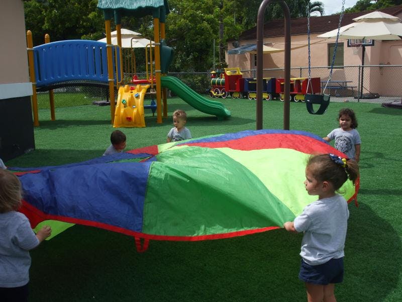 Children playing with a colorful parachute on a playground