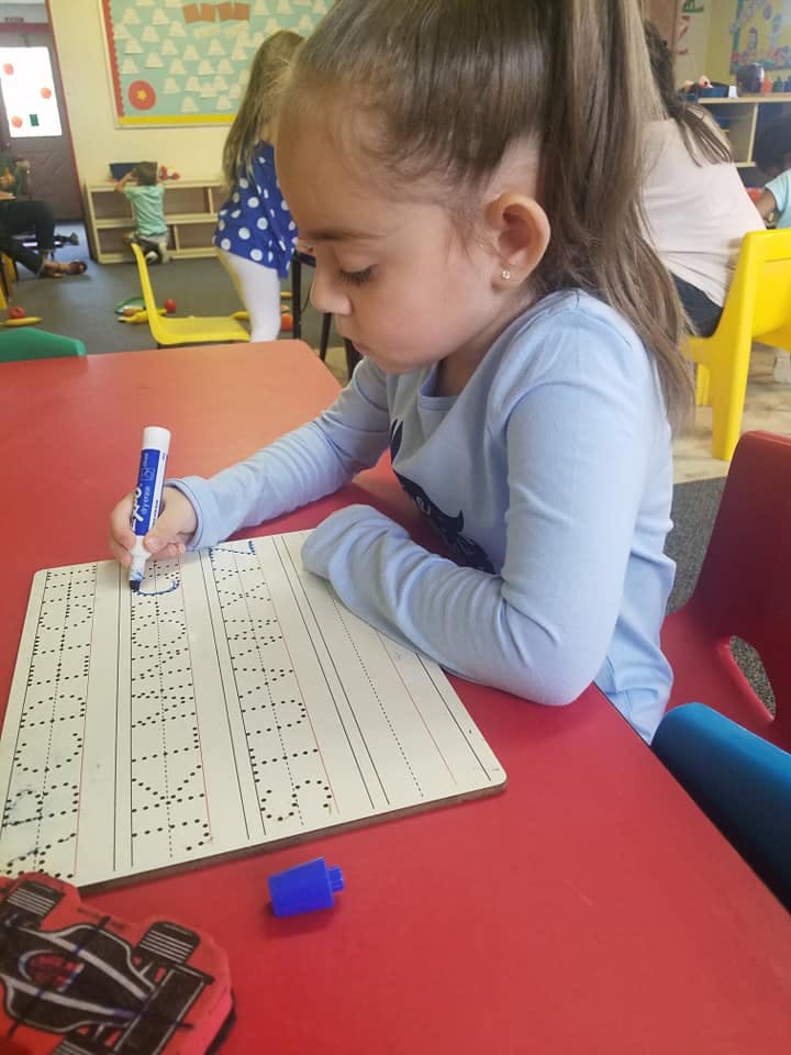 Child writing on a tracing board with a marker