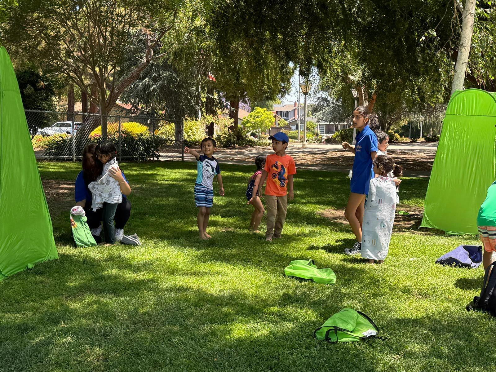 People and children outdoors with green tents