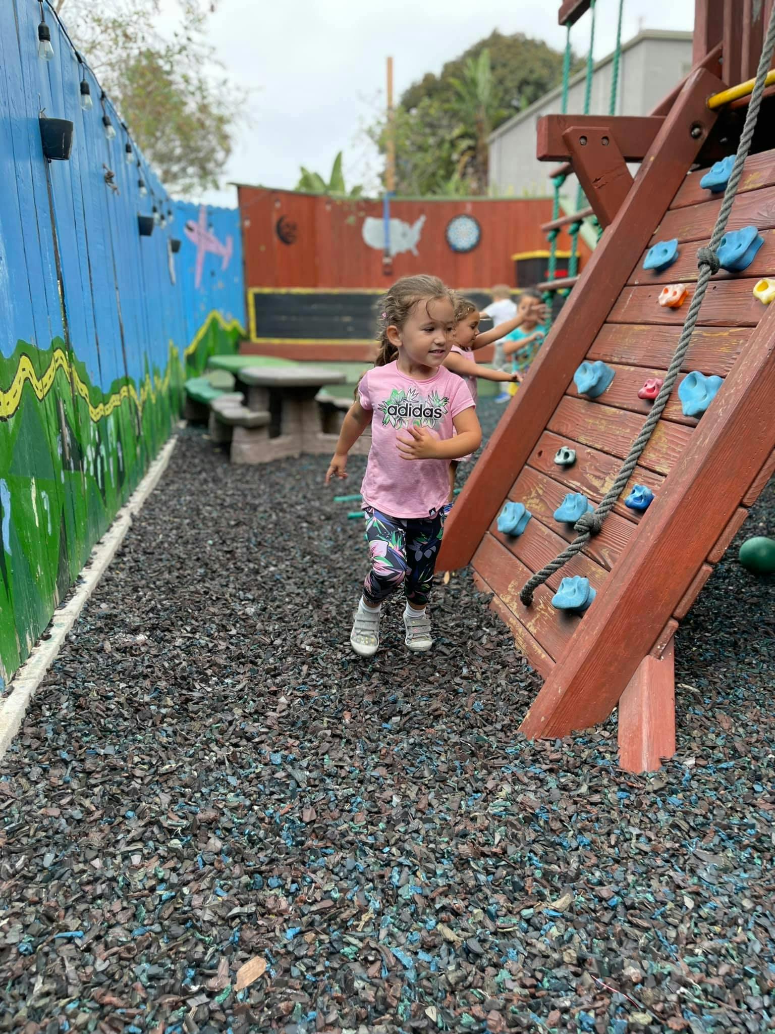 Child walking on playground next to climbing wall