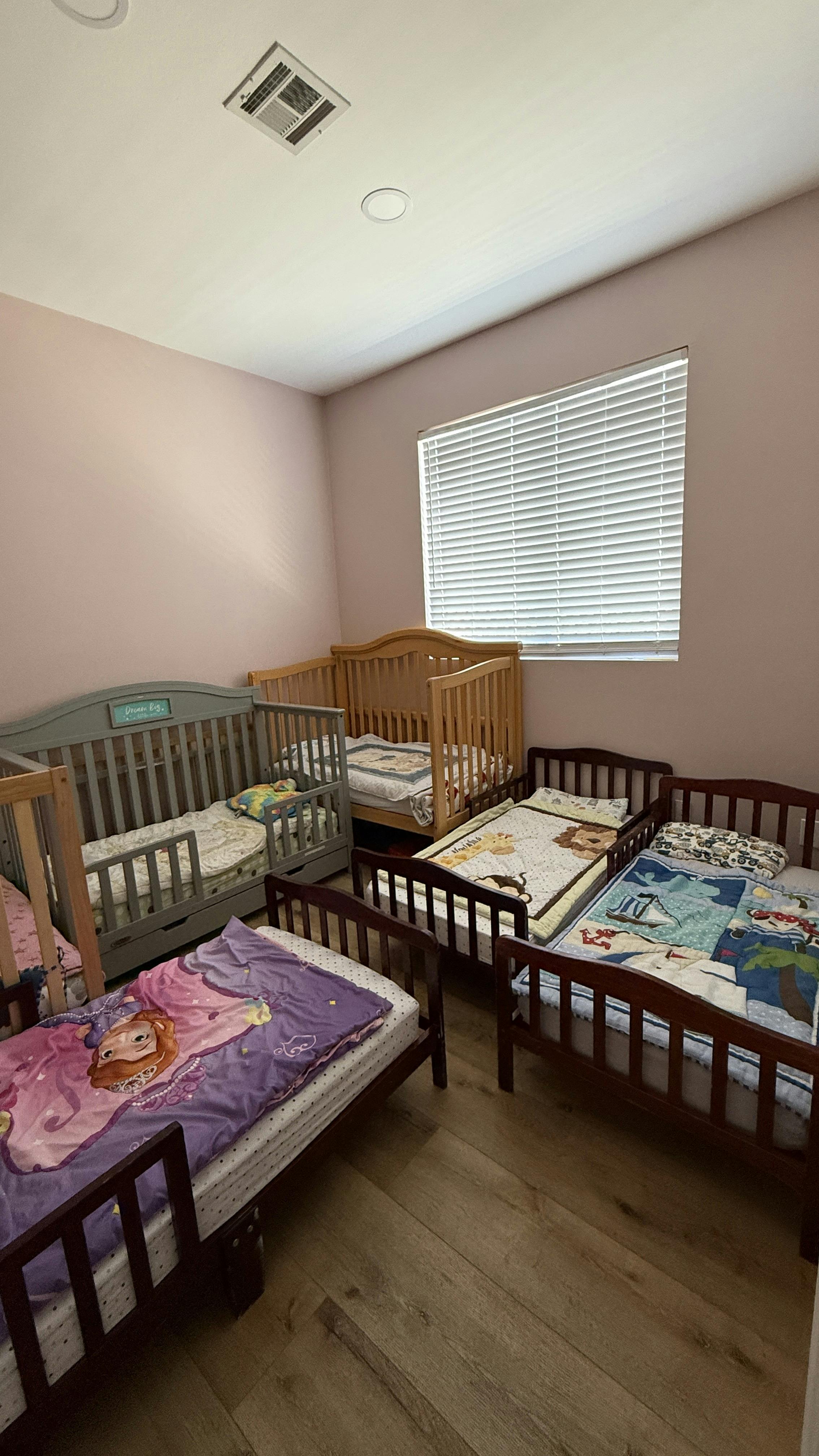 Multiple children's beds and cribs arranged in a room