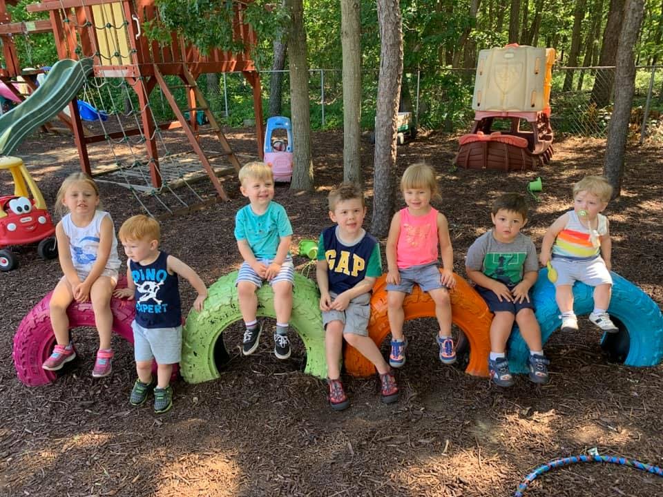 Group of children sitting on colorful tires outdoors