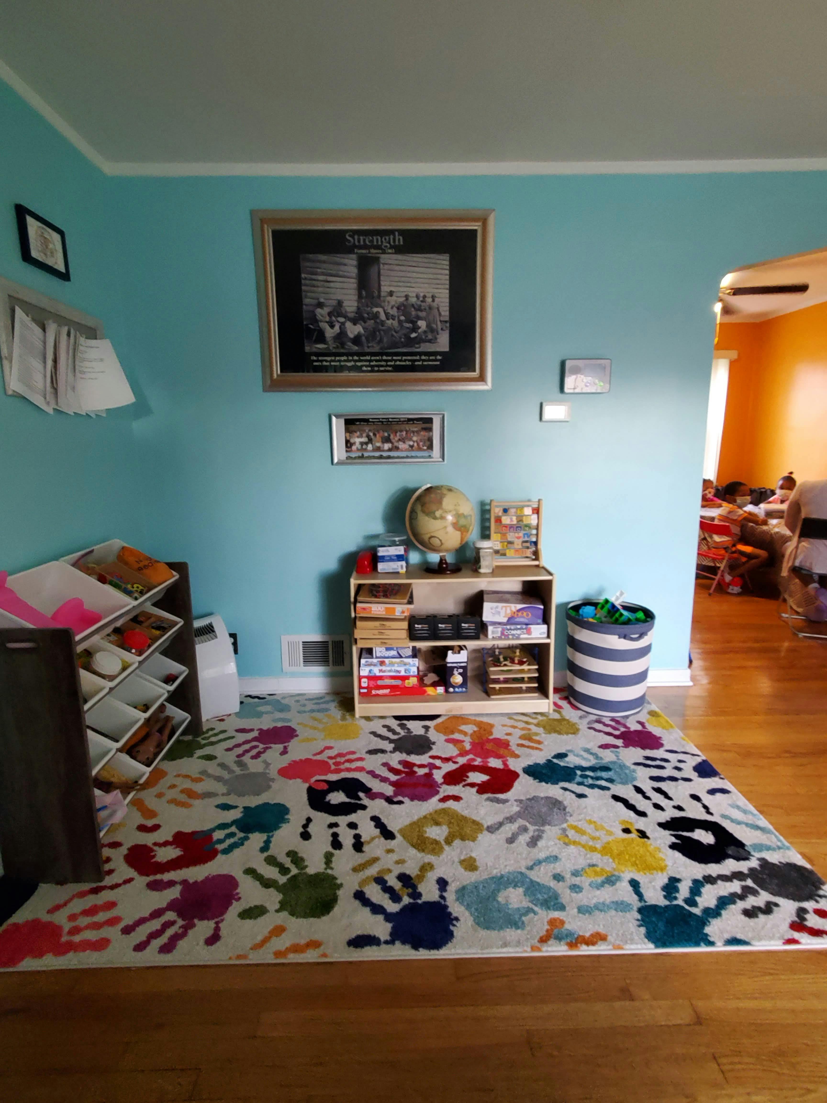 Room with blue walls, a colorful handprint rug, and shelves with items