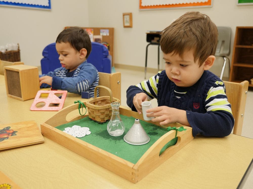 Two children playing with toys at a table in a classroom