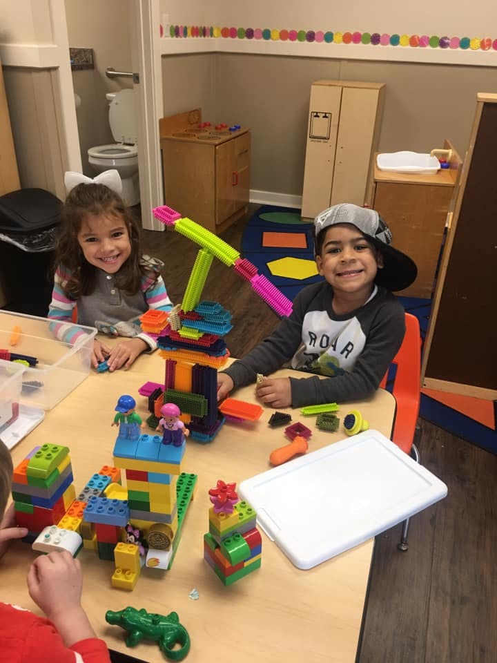 Two children playing with building blocks at a table
