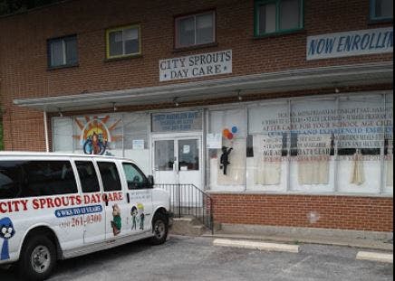 White van parked in front of a brick building with "City Sprouts Day Care" sign