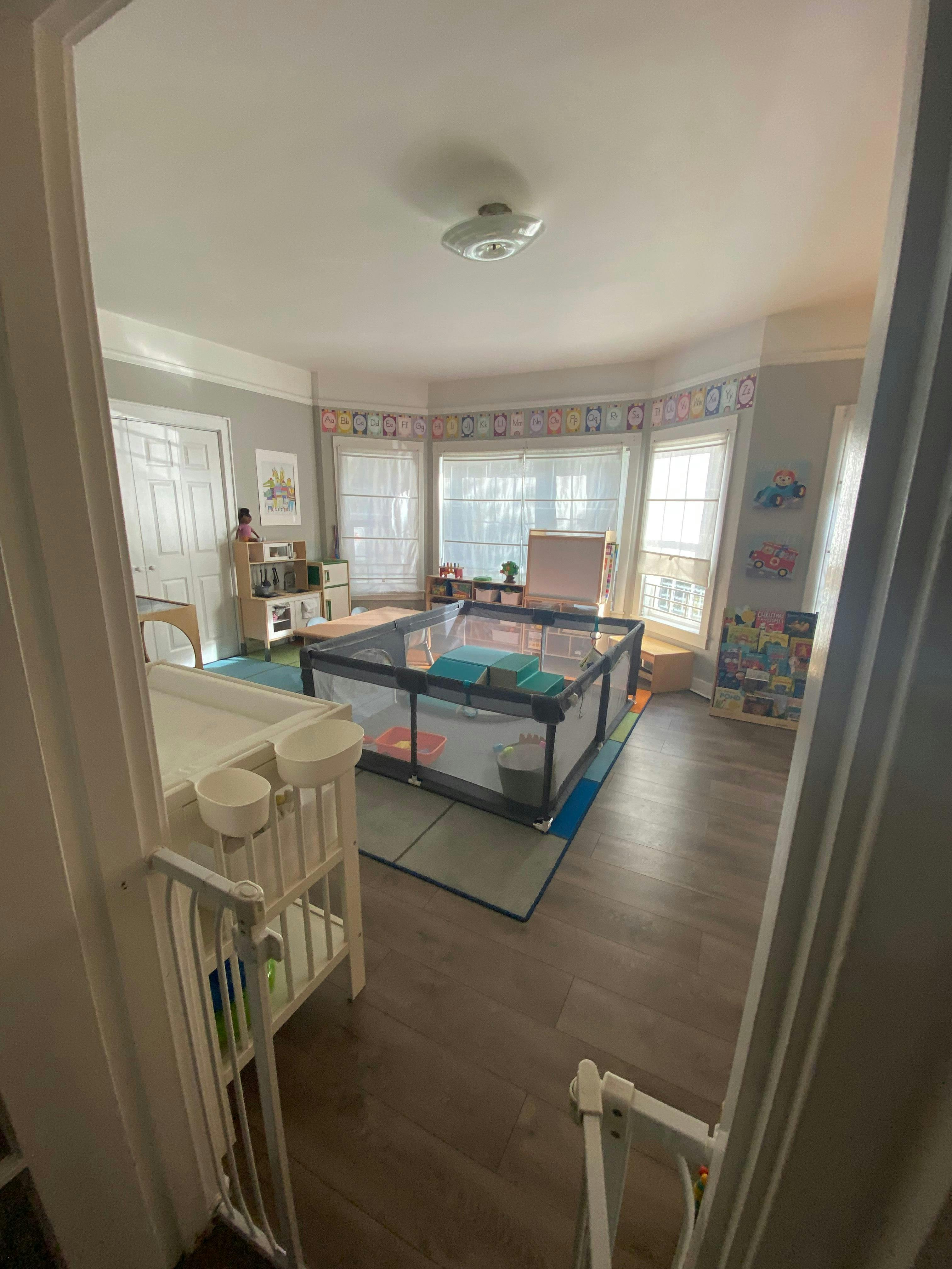 Playpen in a room with a changing table and bay windows