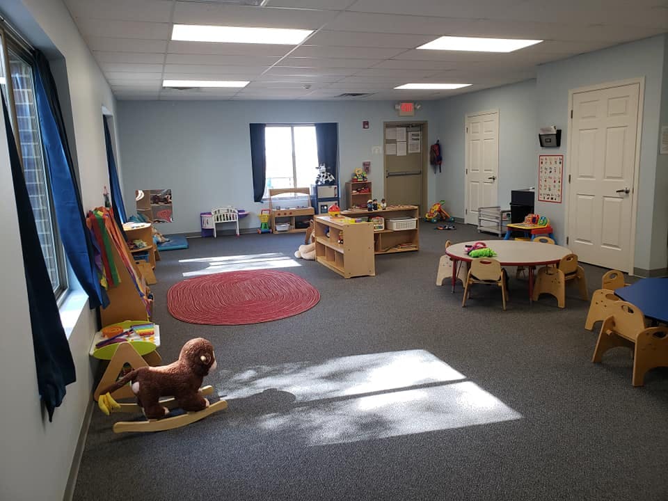 Empty classroom with small tables, chairs, and toys