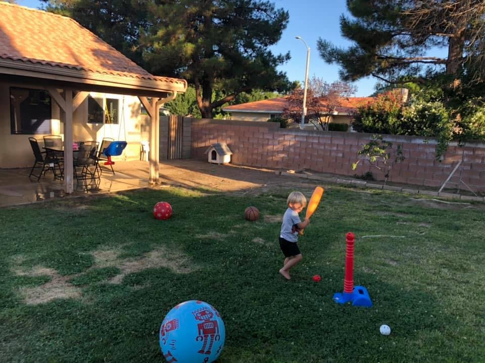 Child playing T-ball in a backyard