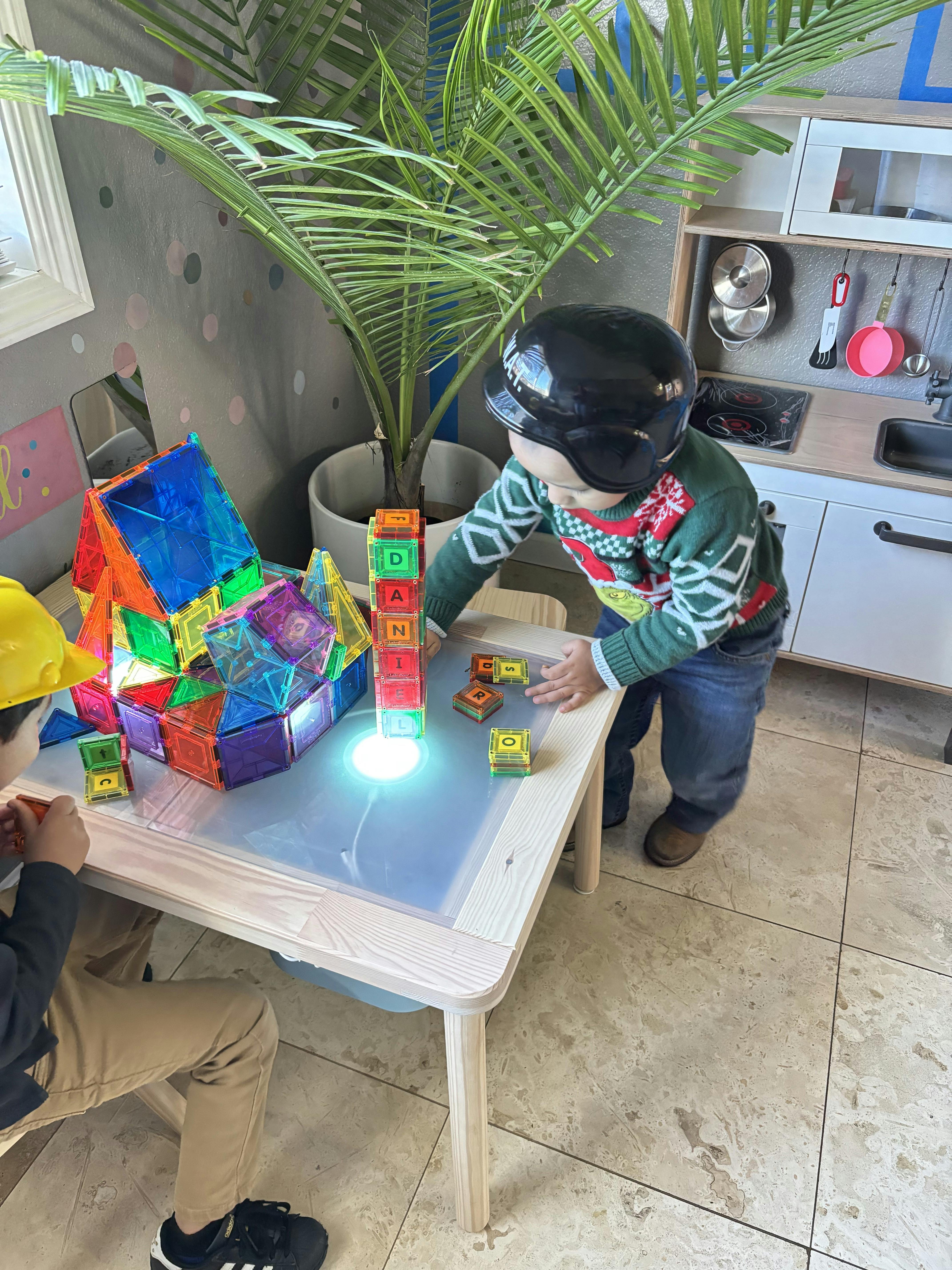 Child in helmet playing with magnetic blocks on a light table