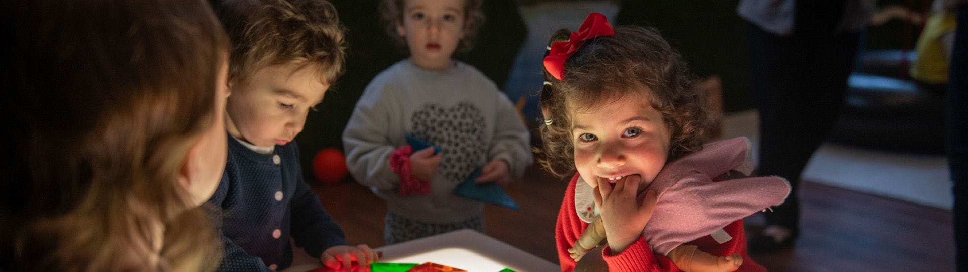 Three young children playing together at a light table