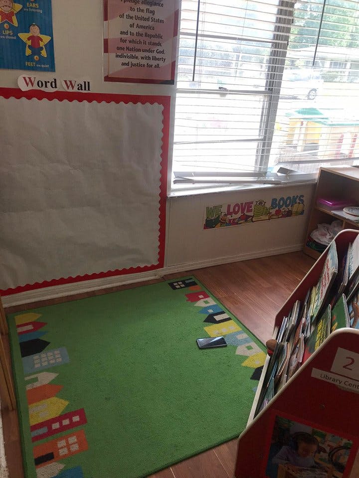 Classroom corner with a green rug, window, and book display