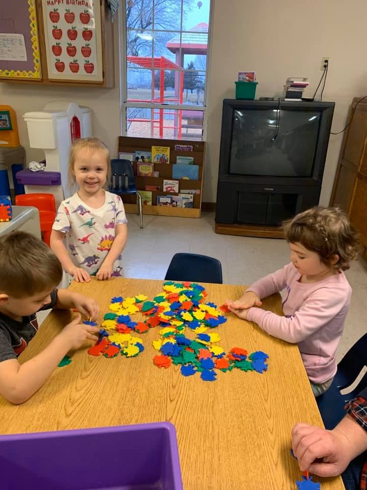 Three children playing with colorful interlocking toys at a table