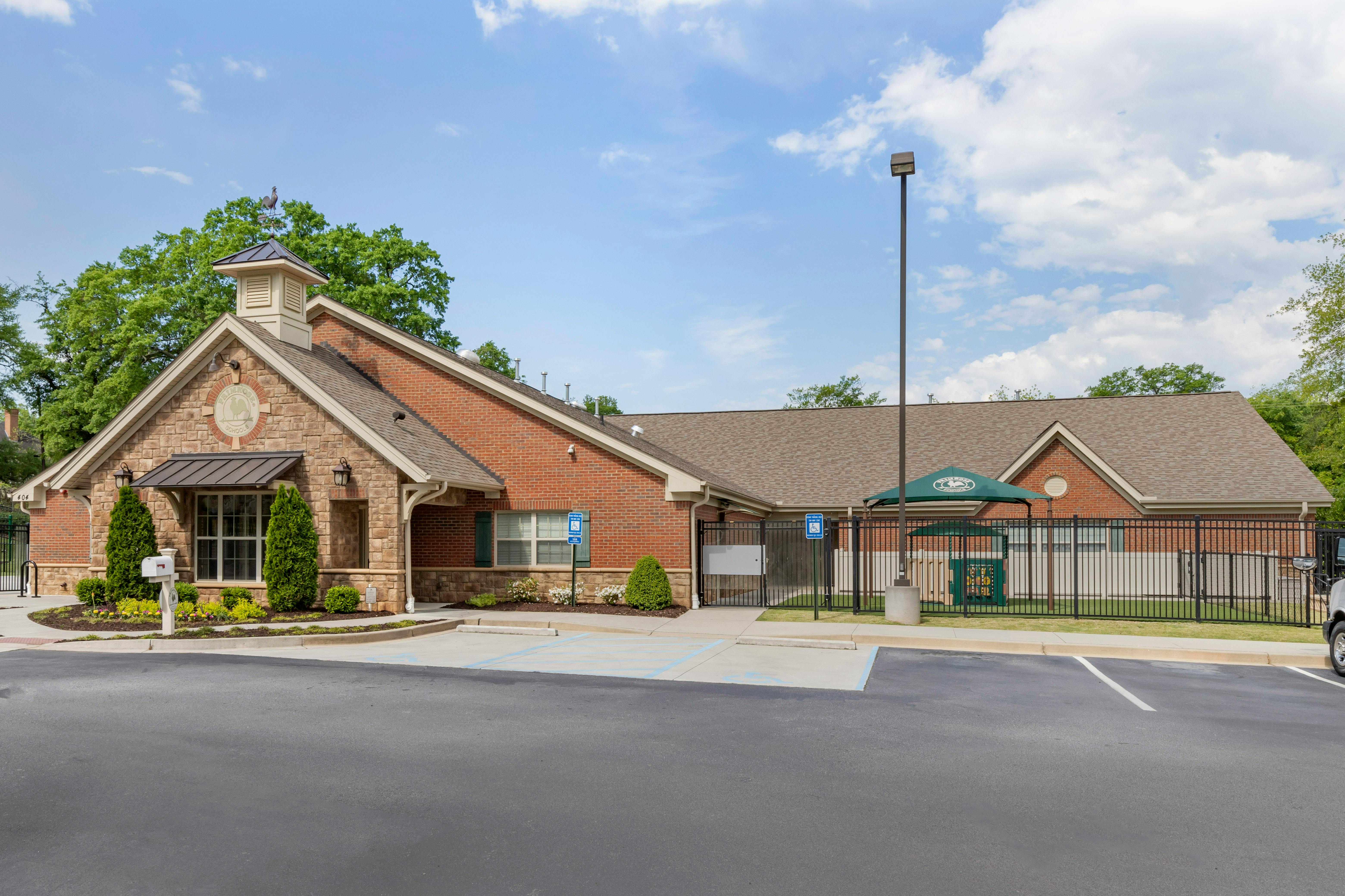 Brick and stone building with a parking lot and a fenced play area
