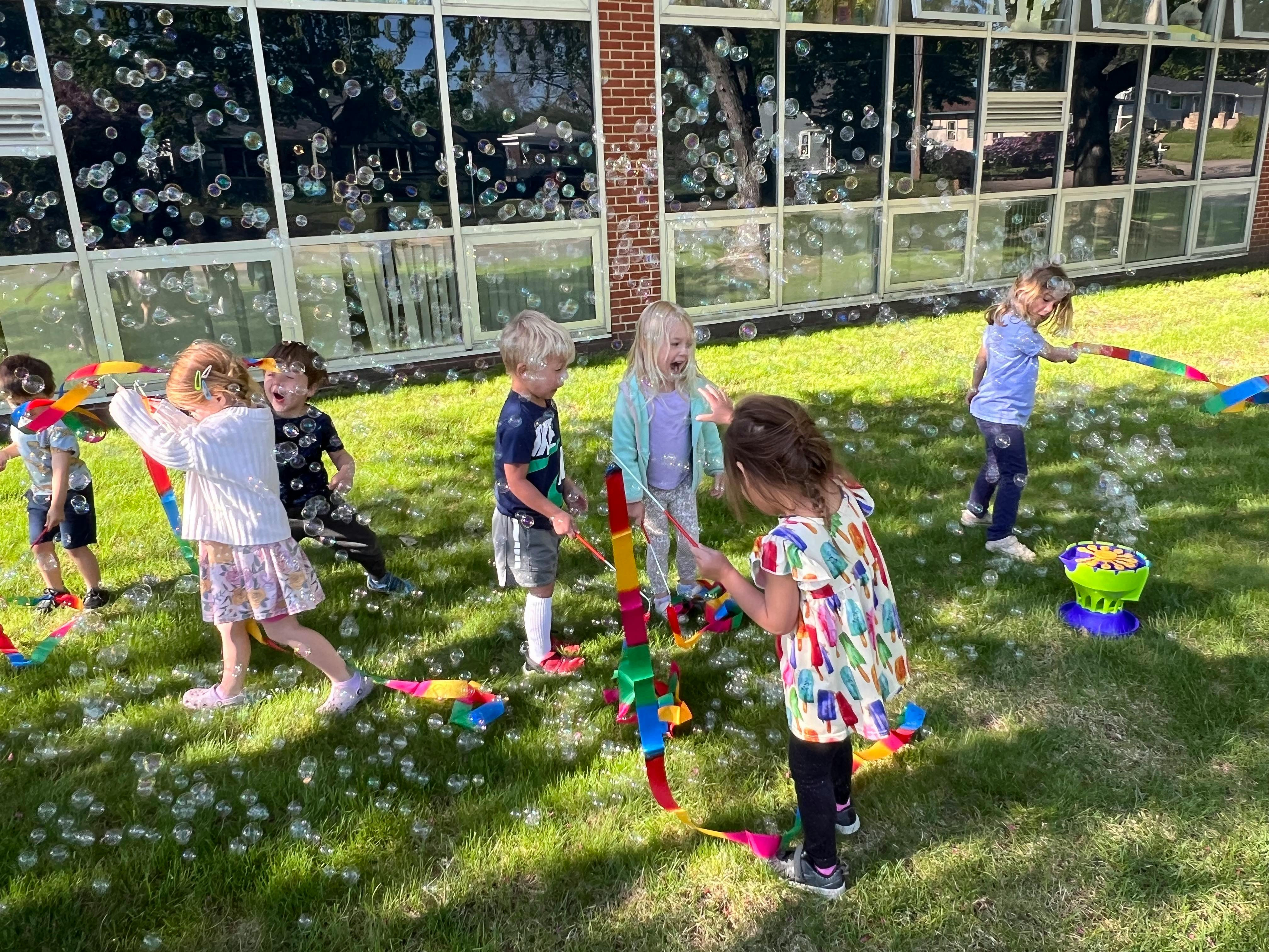Children playing with bubbles and colorful toys on grass