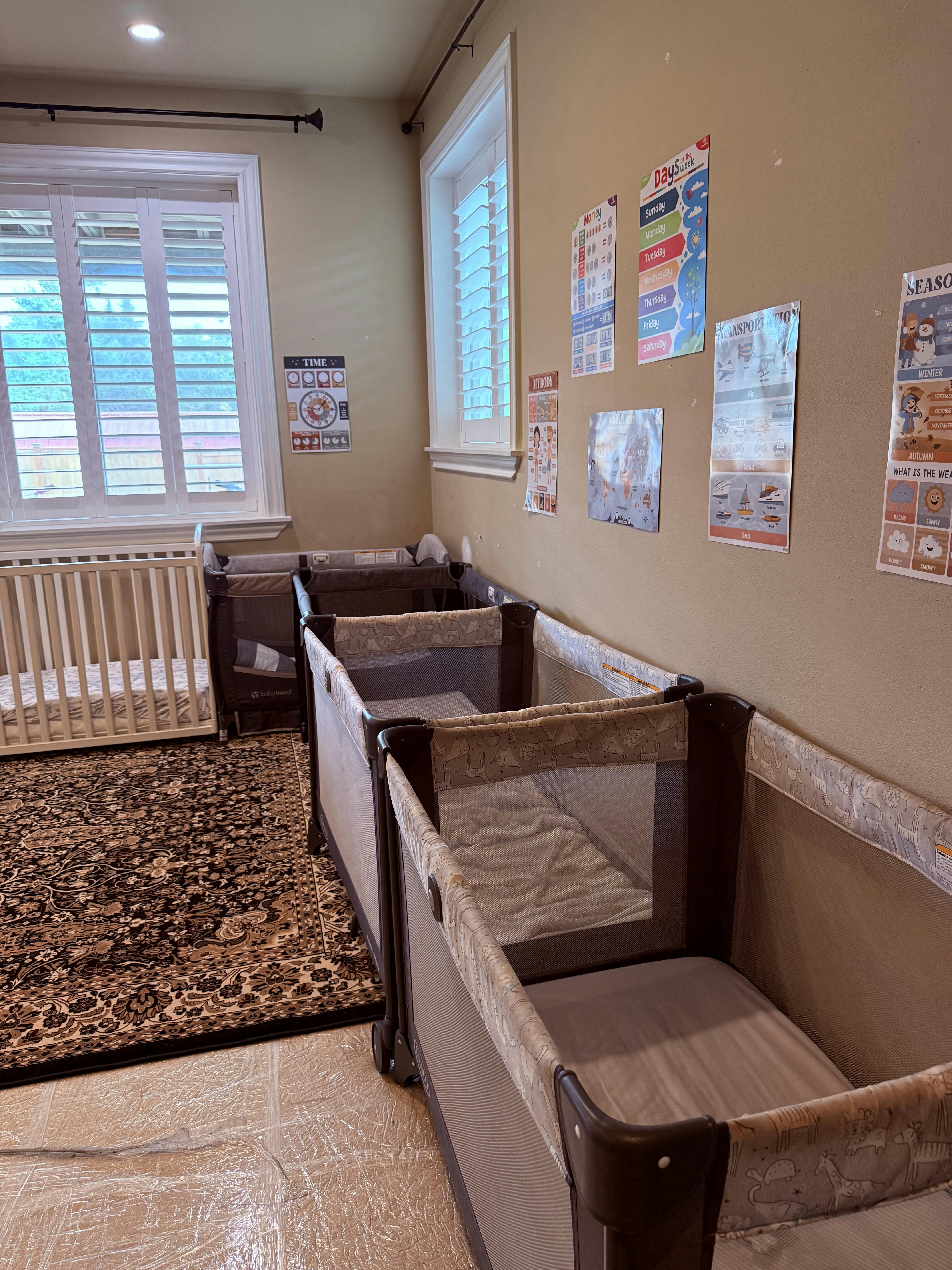 multiple portable cribs in a room with educational posters on the wall