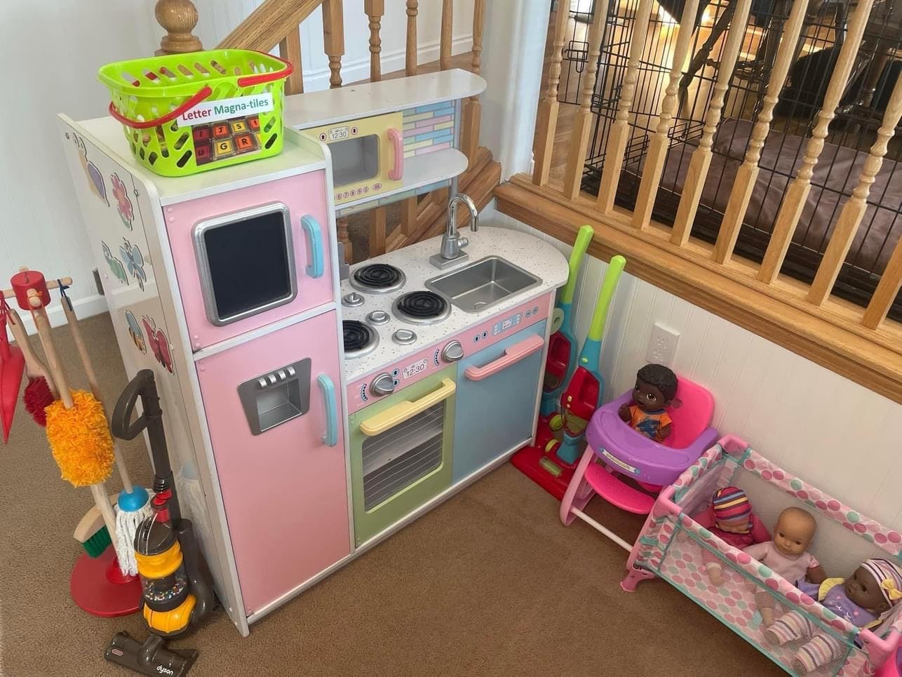 Child's play kitchen with toy cleaning supplies and dolls