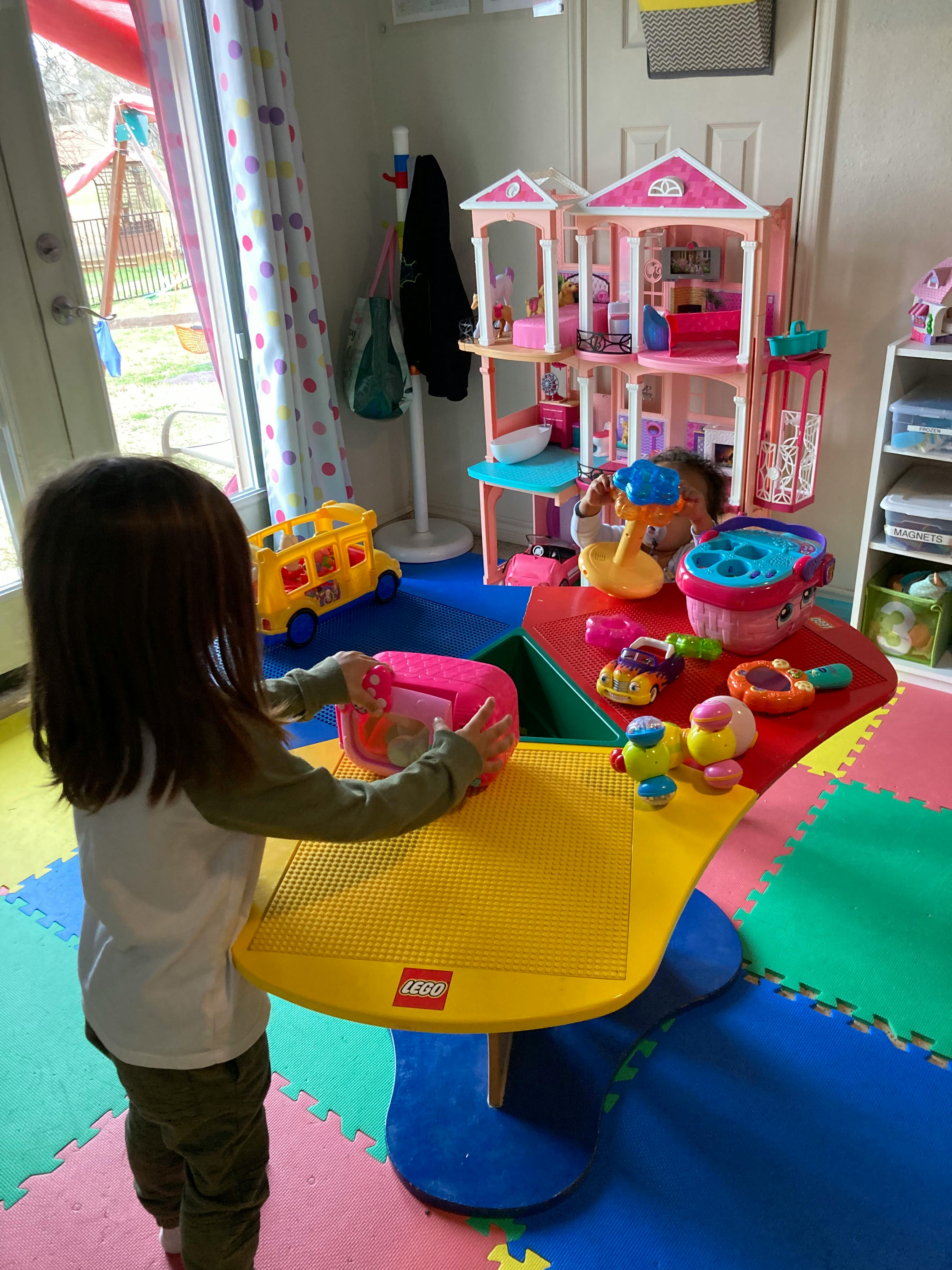 Child playing with a pink toy on a yellow table
