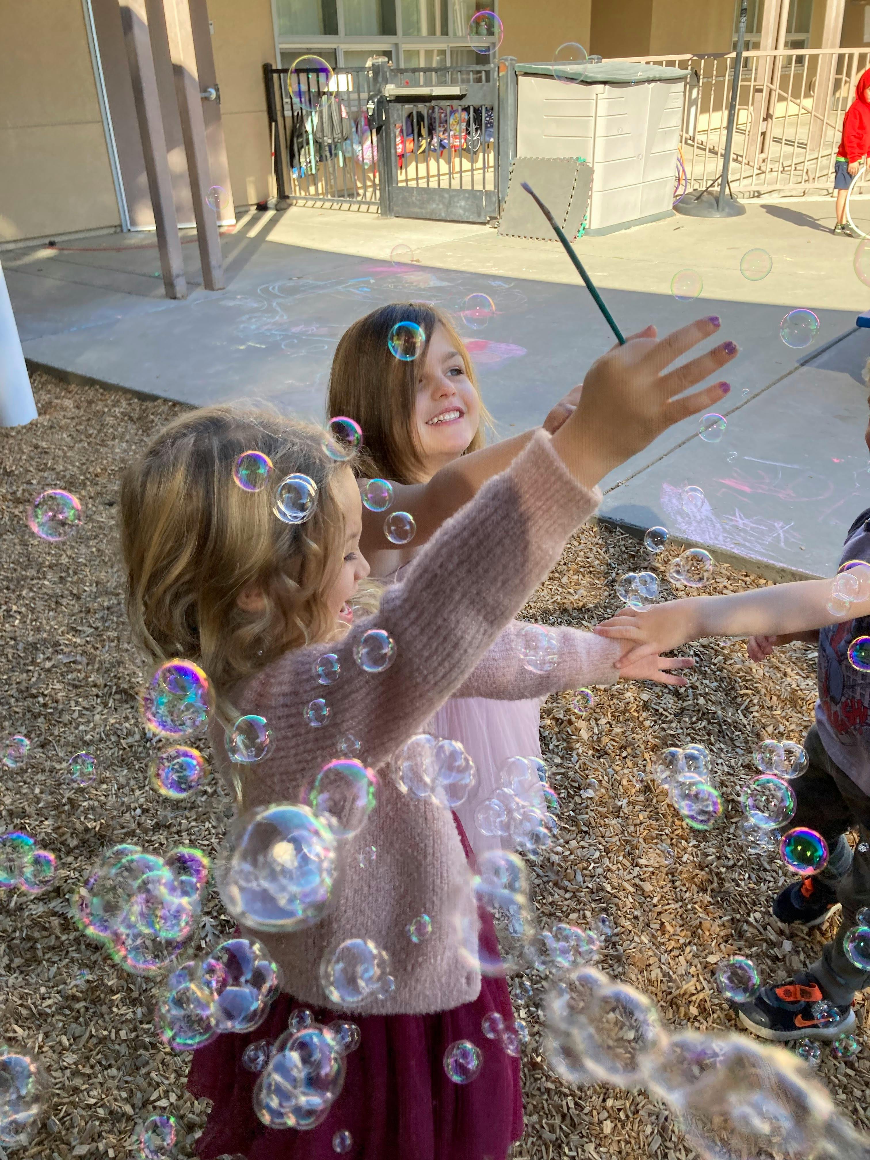 Two children playing with bubbles outdoors