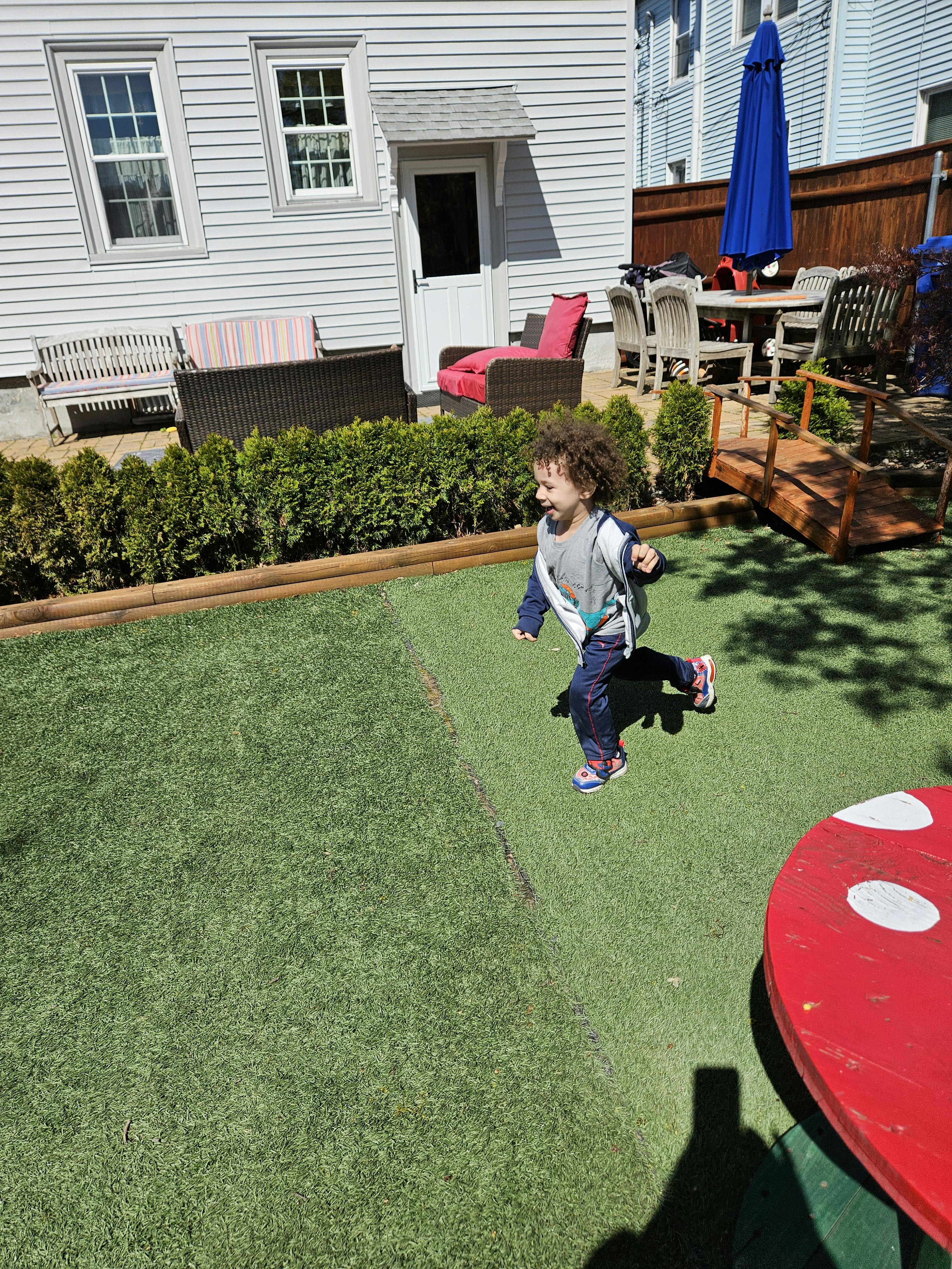 Child running on artificial grass in a backyard