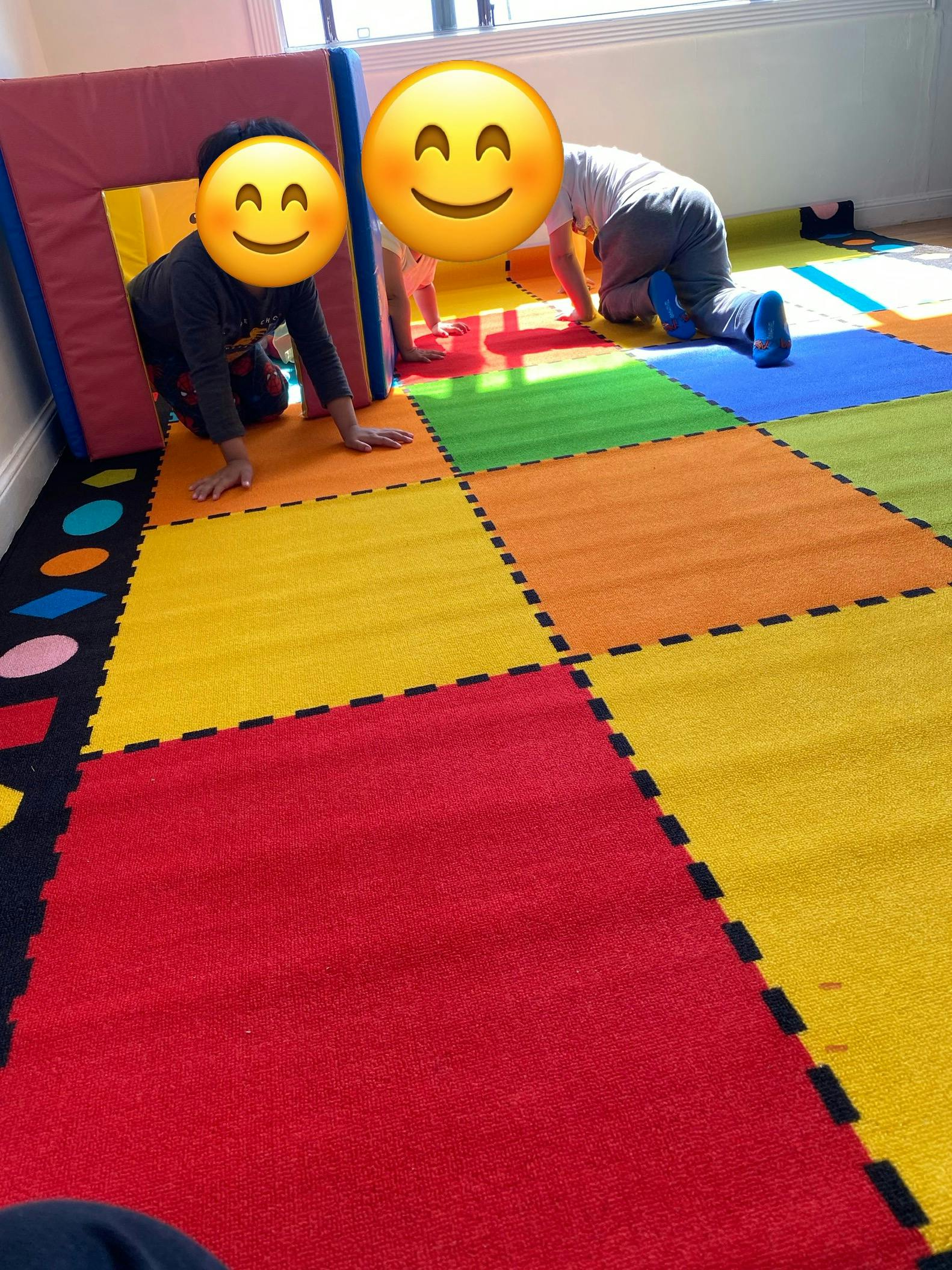 Two children crawling on a colorful playmat