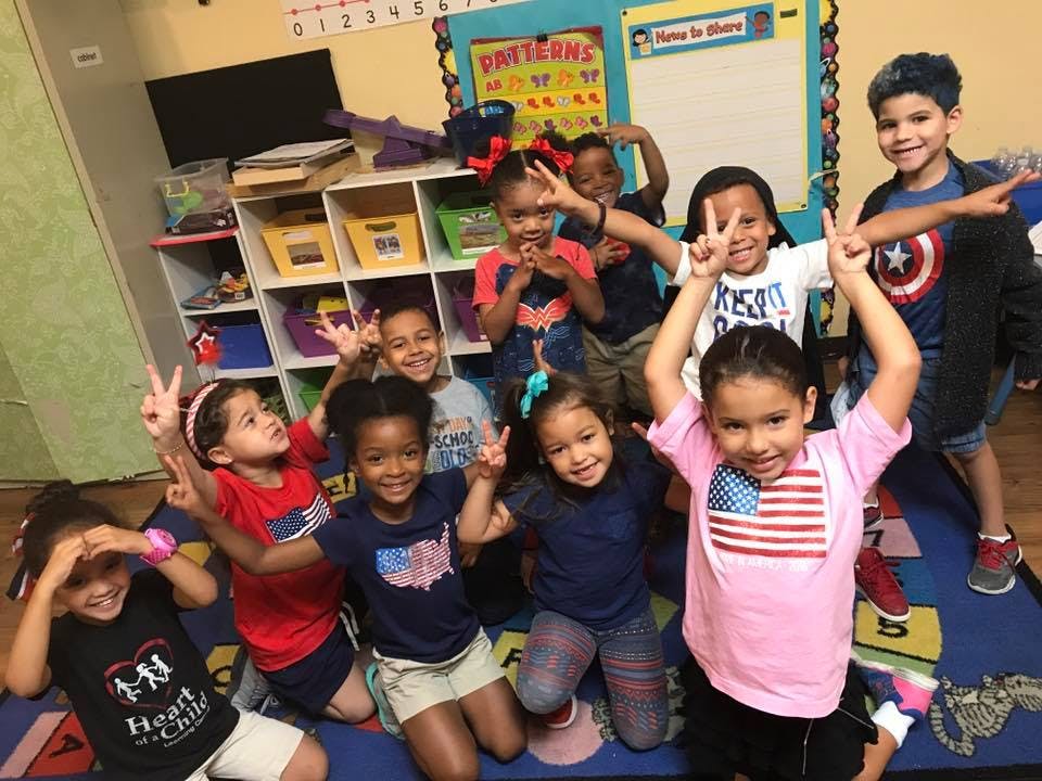 Group of children making peace signs in a classroom