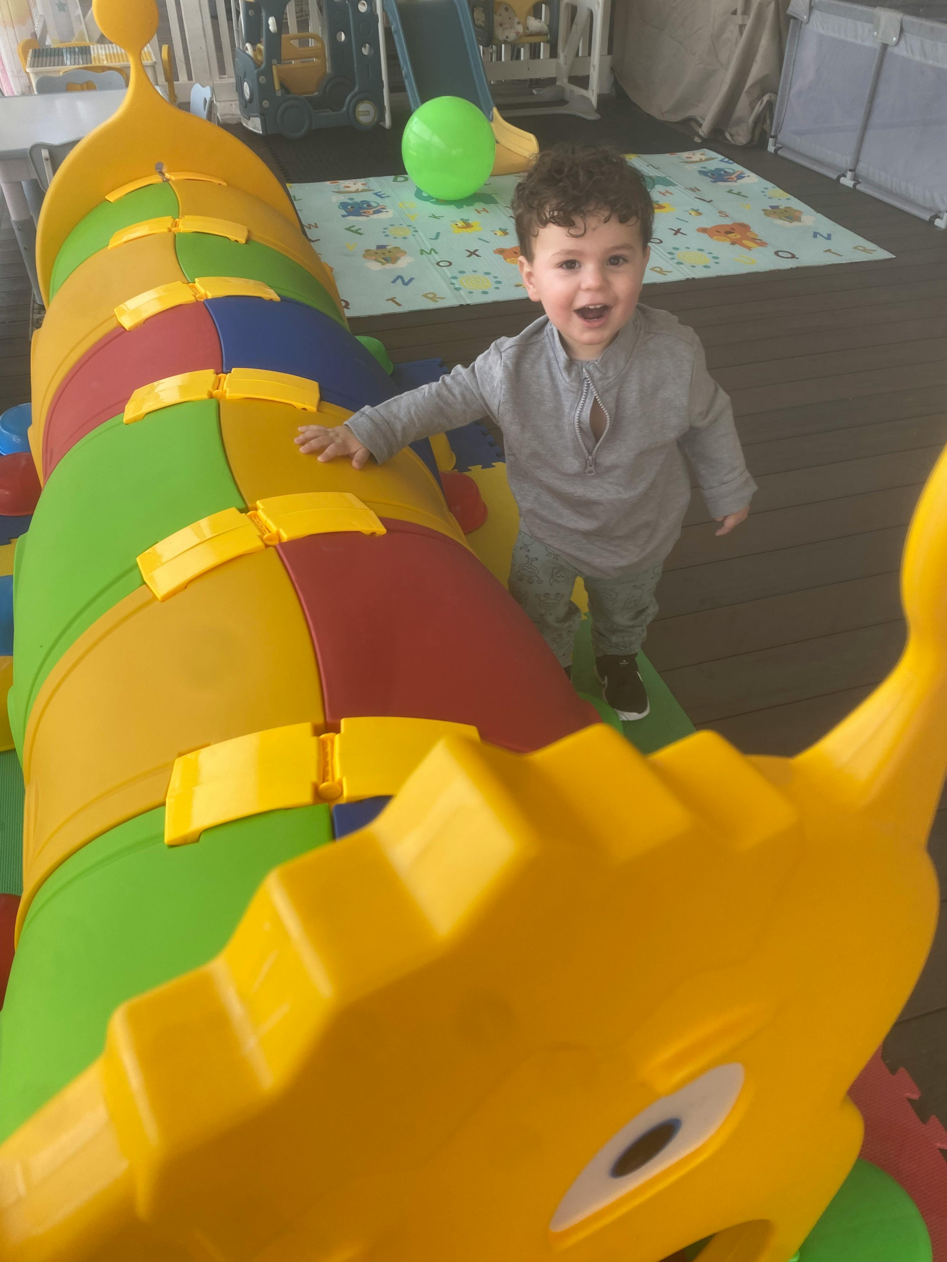 Child peeking out from a colorful play tunnel